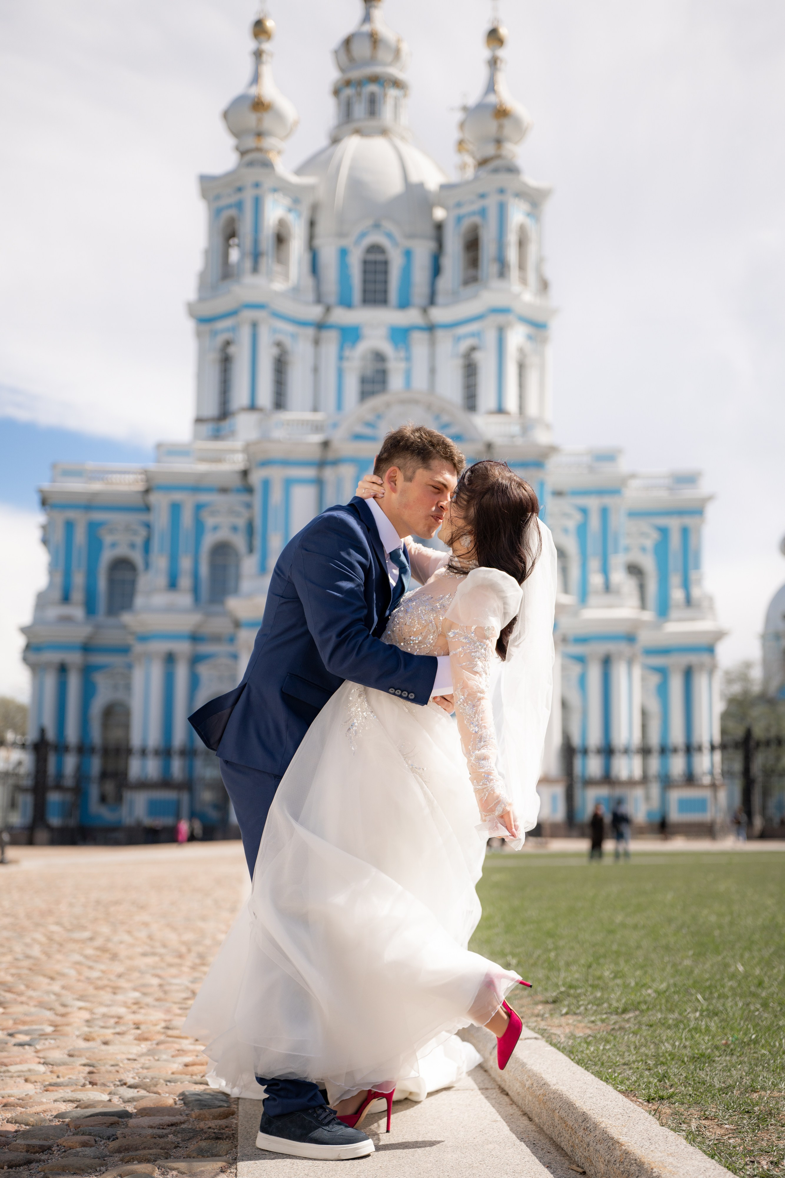 Свадебная фотосессия у Смольного собора. Жених красиво обнимает невесту.
