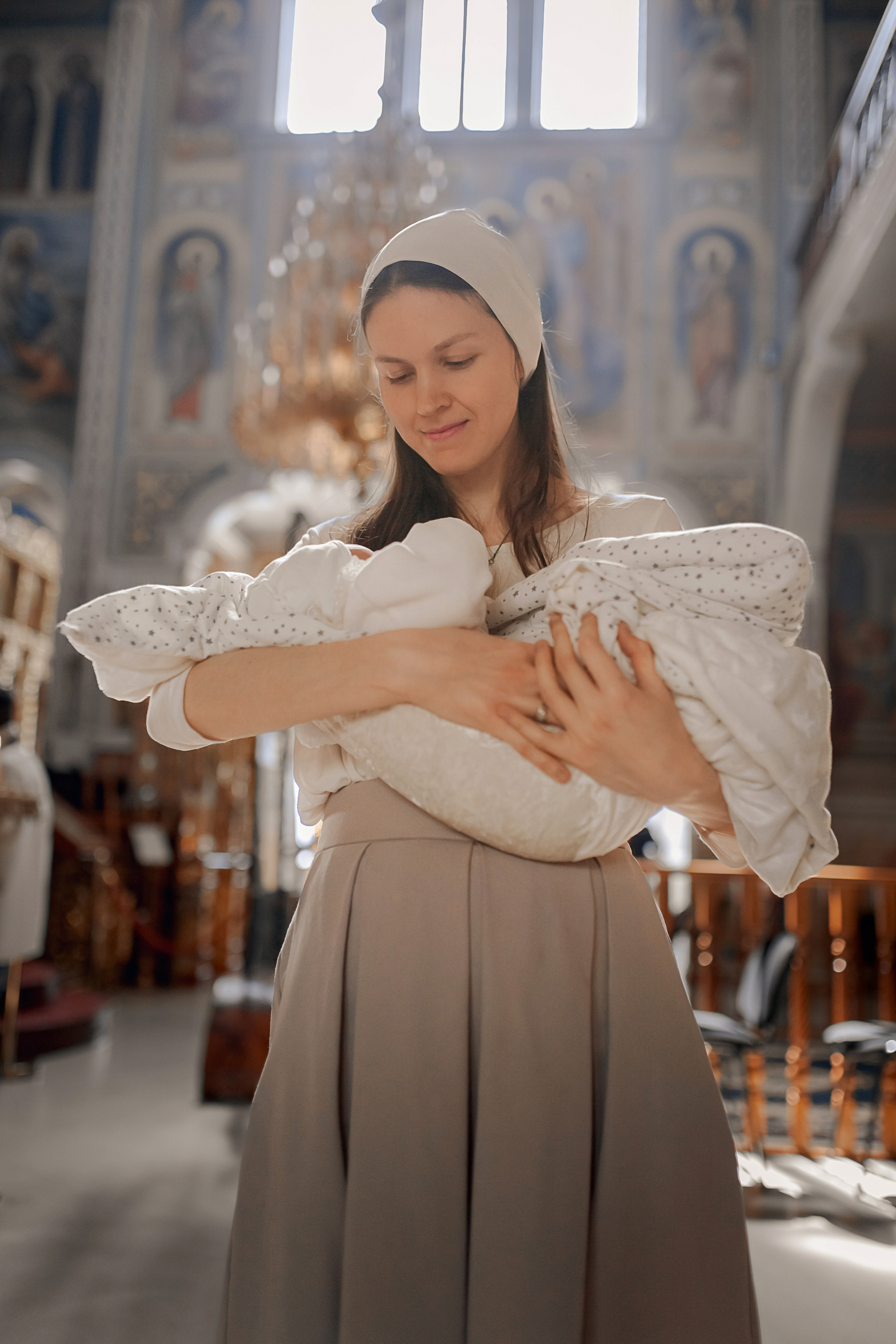 крестная мама держит ребенка после того как прошла огласительные беседы в Ташкенте