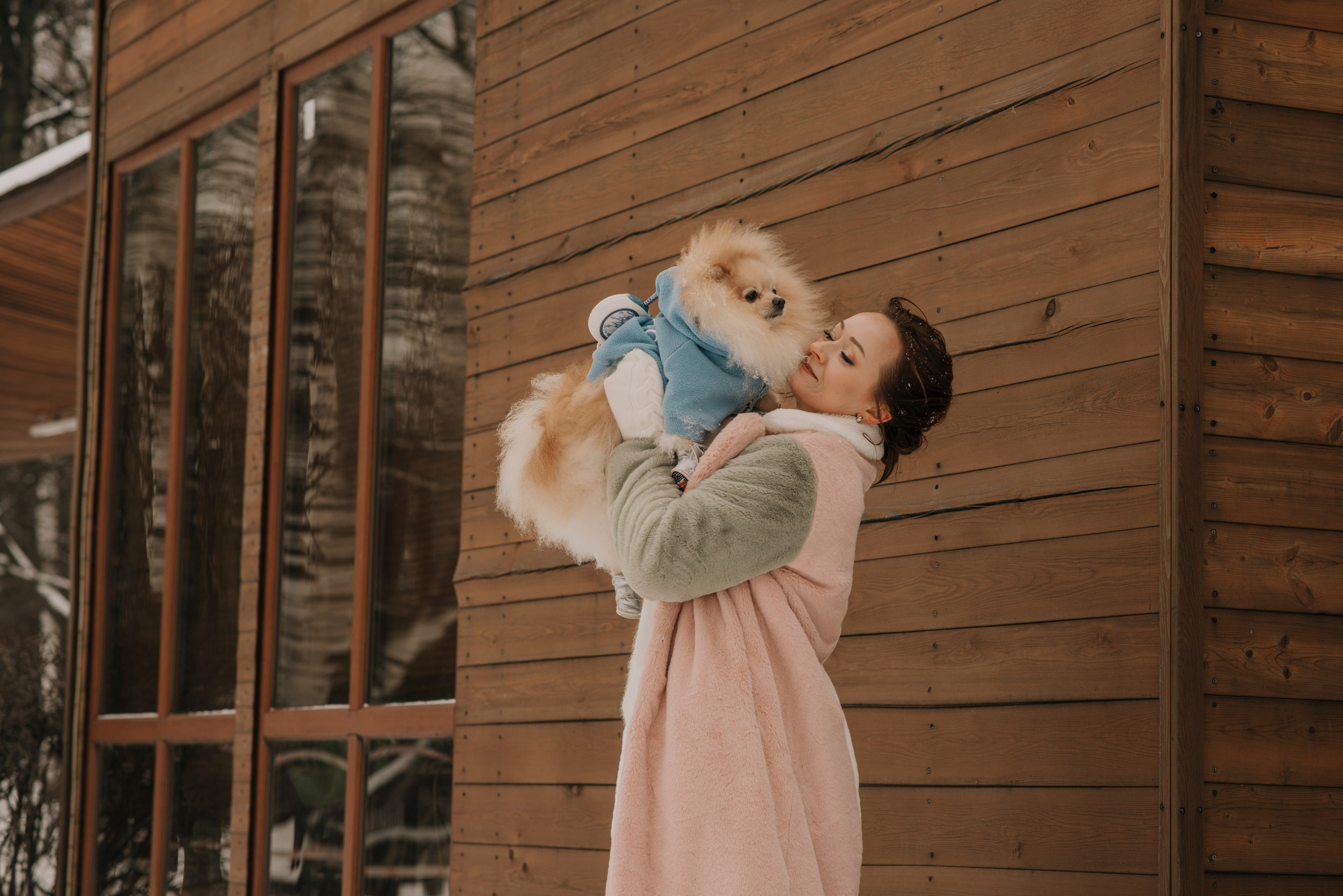 Фотосессия с собакой шпицем зимой в парке, девушка в розовой шубке держит шпица на руках