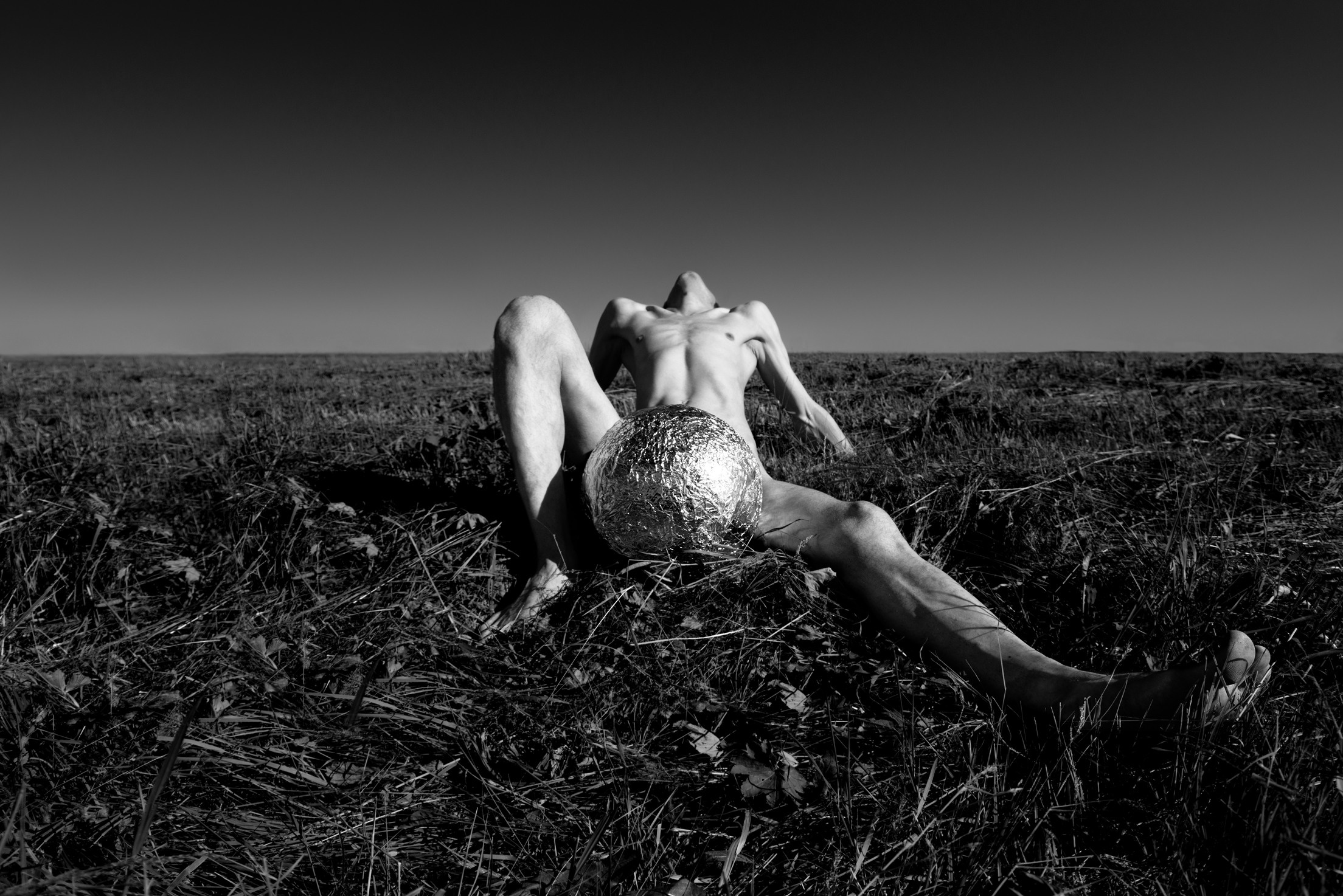 мужская ню фотосессия, обнаженный мужчина в поле с серебряным шаром 