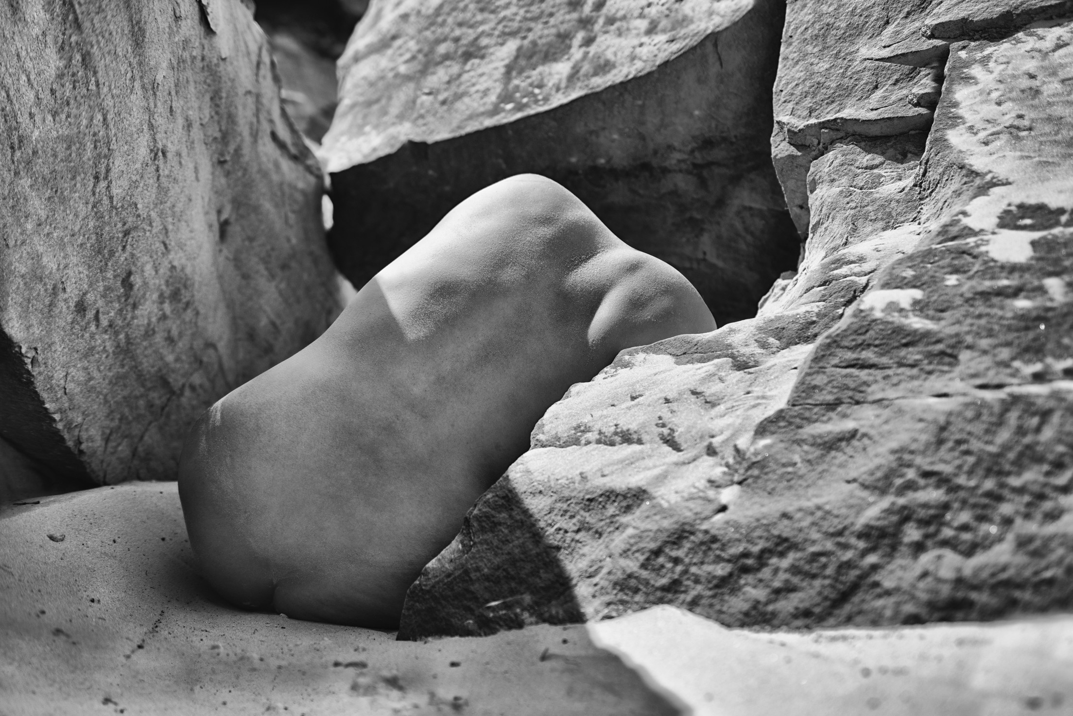 тело спиной среди камней в ярком солнечном свете 