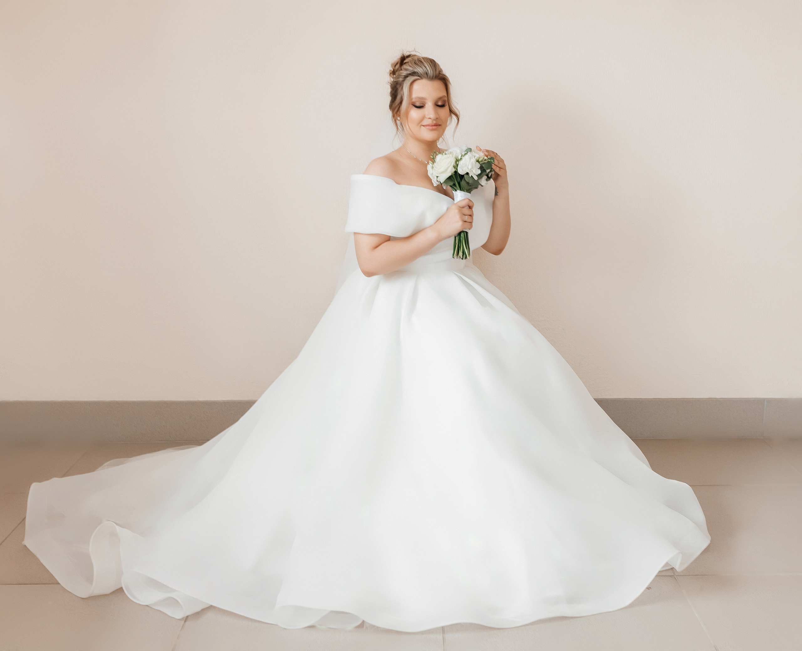 Невеста в платье со шлейфом сидит на стуле