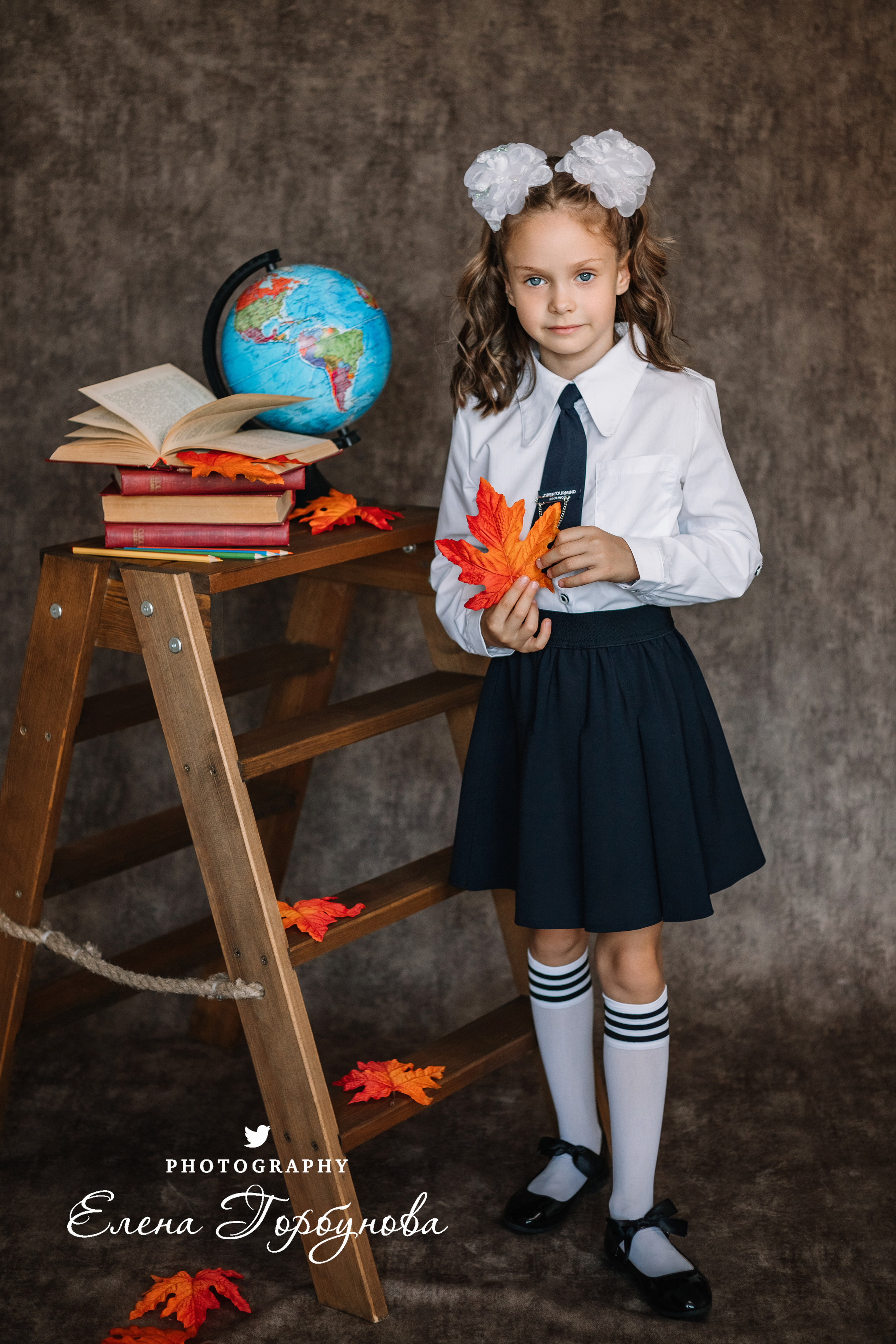 Фотограф Елена Горбунова Пермь. школьный портрет. фотосессия на 1 сентября. девочка в школьной форме с глобусом и книжками, с осенними листьями. Листья клена на портрете. школьный портрет в студии на фото. художественный портрет. школьный фотограф.