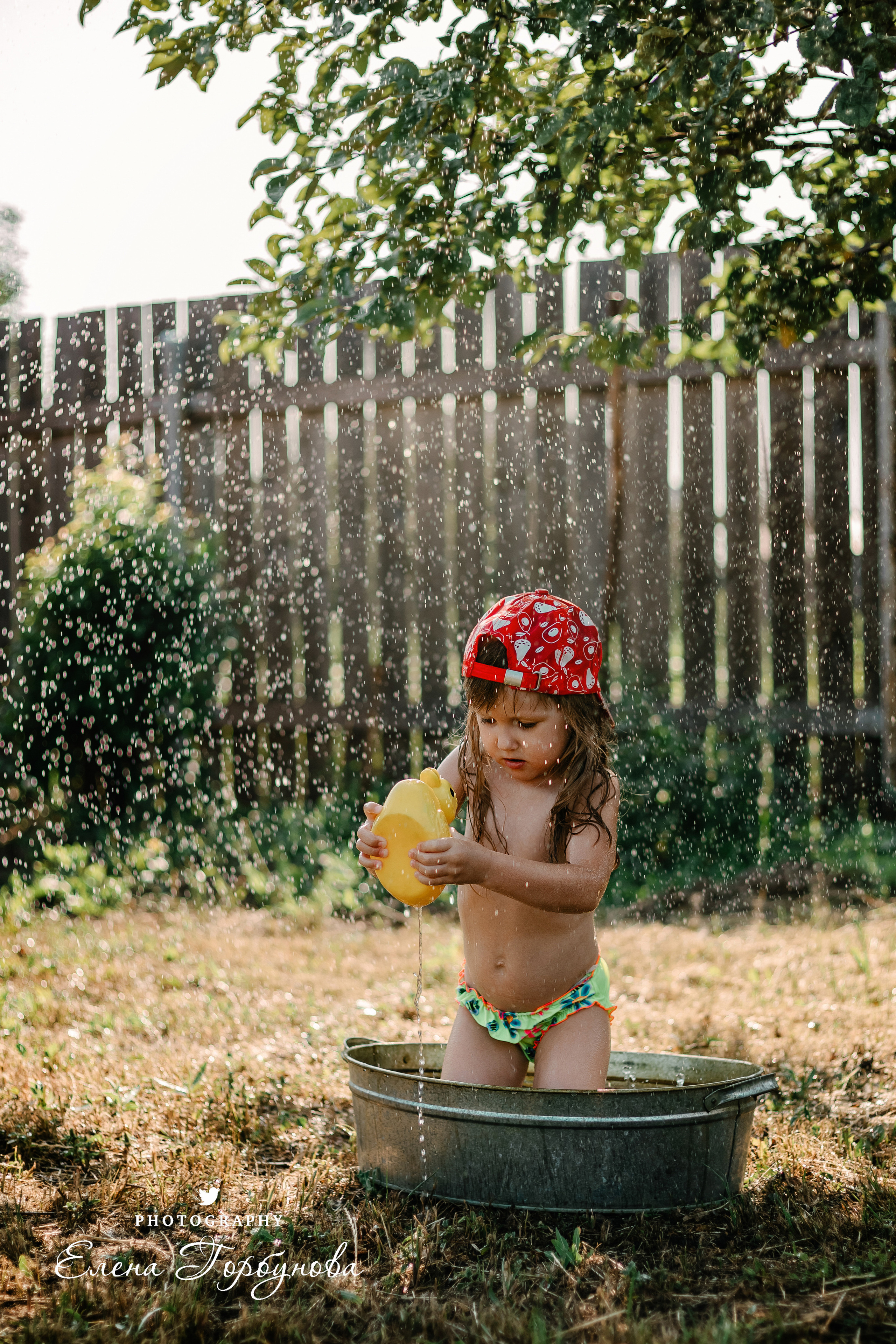 Детская фотосессия на природе на даче летом в тазике под яблоней с брызгами воды, с фонтаном с уточкой