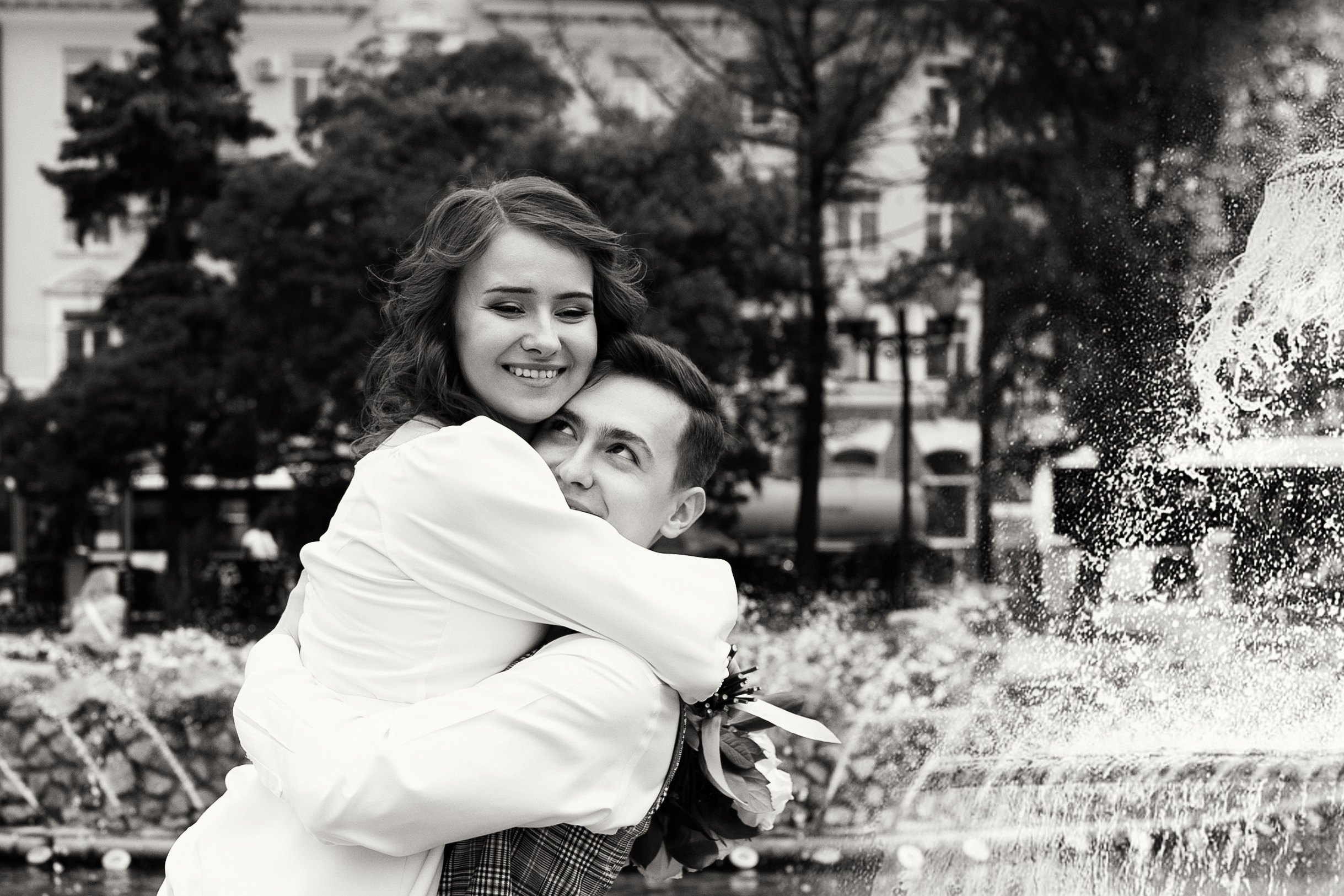 Невеста и жених кружатся в брызгах фонтана с букетом