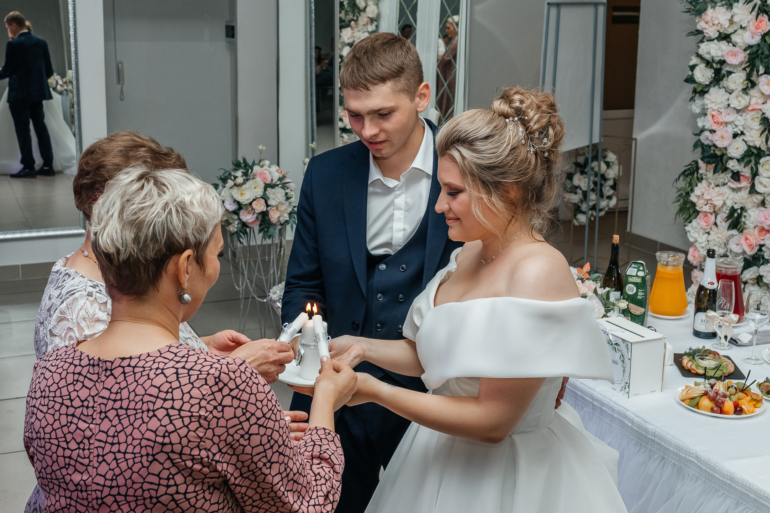 Родители жениха и невесты зажигают свечи. Репортажное фото с банкета