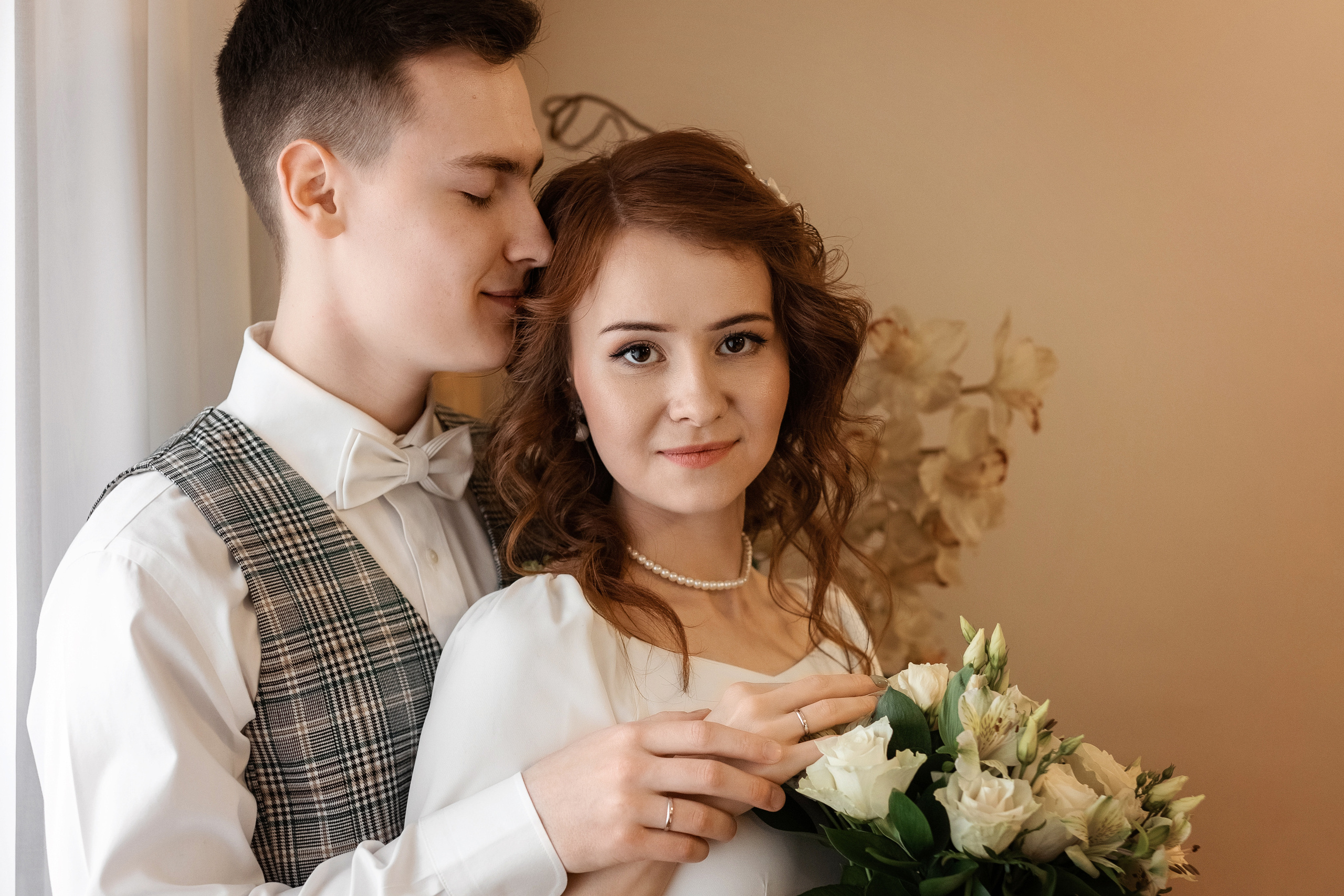 Молодожены стоят у окна в ЗАГСе