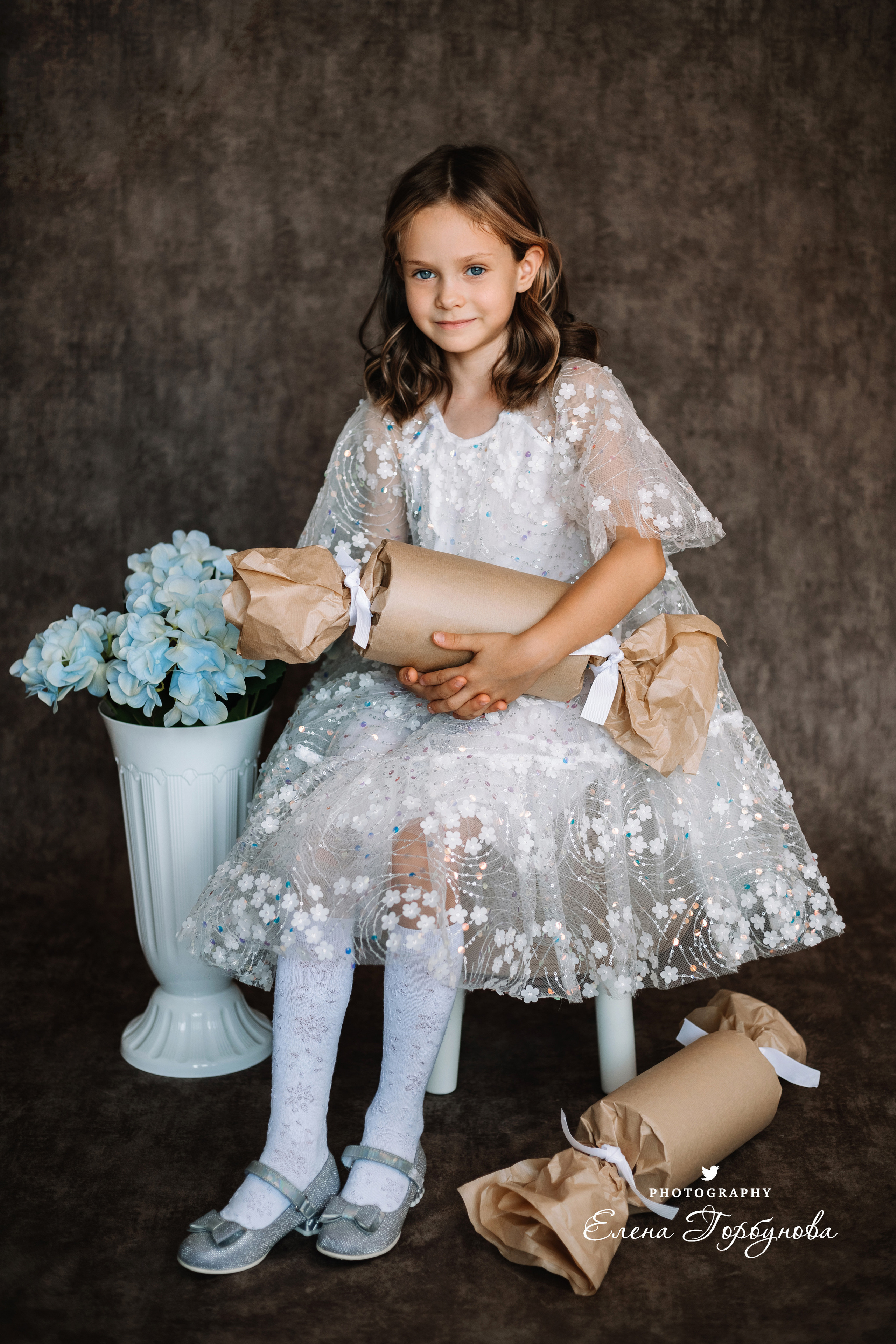 Фотосессия в садике Пермь фотограф Елена Гобунова Девочка в белом платье позирует на стуле с цветами Открытка для мамы. Детская фотосессия. Детский портрет в студии