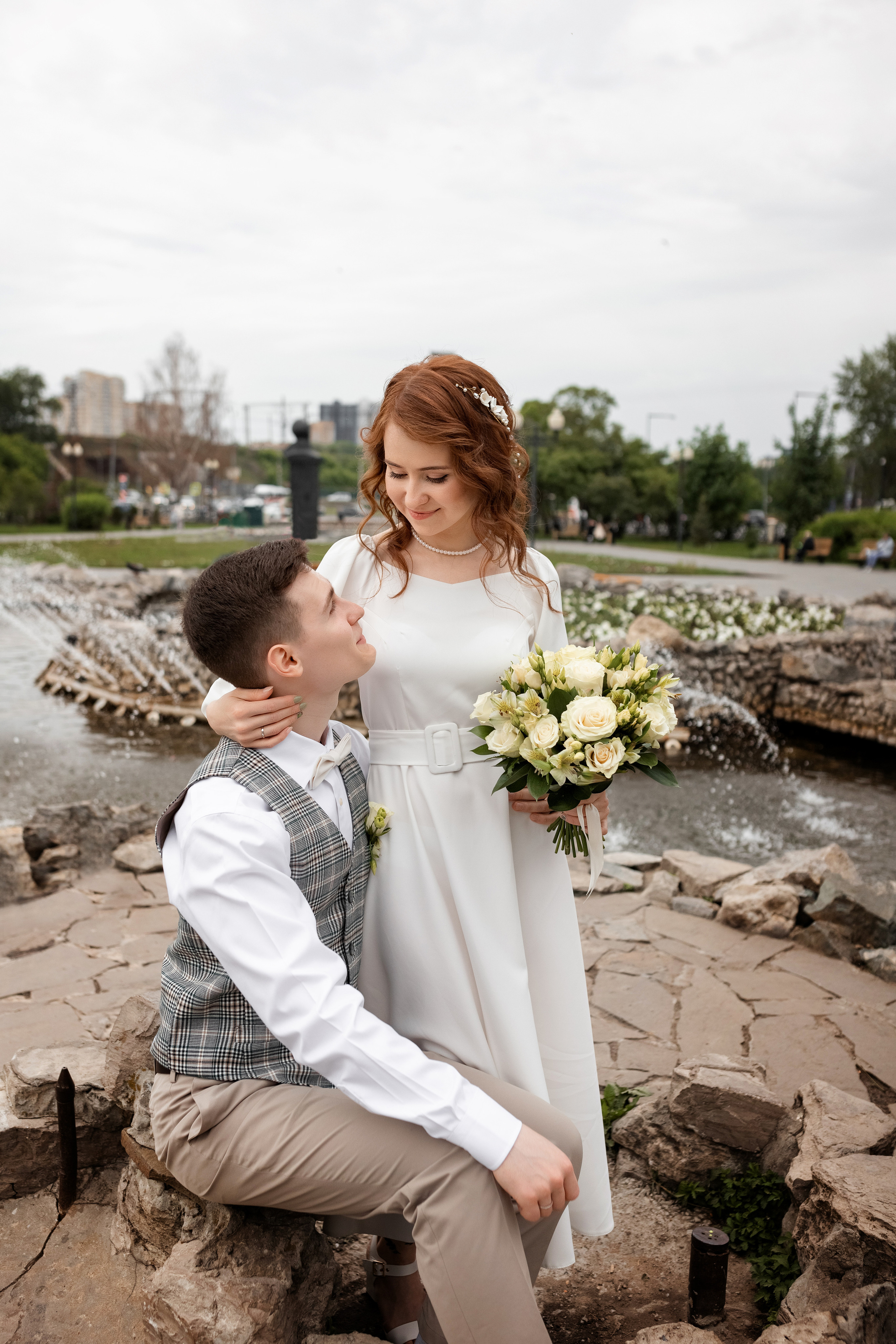 Молодожены на свадебной фото прогулке у фонтана