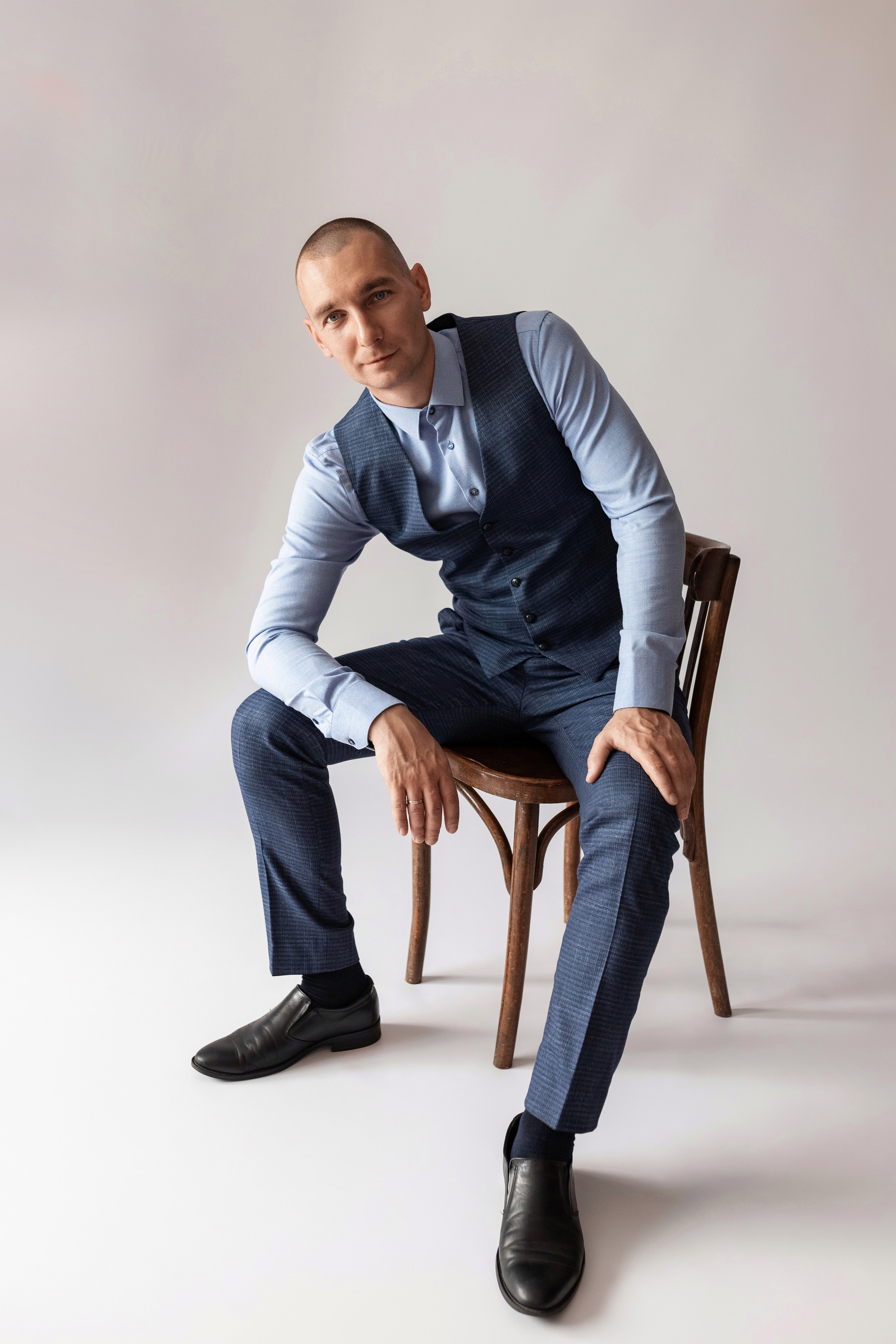 Индивидуальная мужская фотосессия в студии минимализм. на стуле. на белом фоне, на бежевом фоне. В классическом костюме тройка