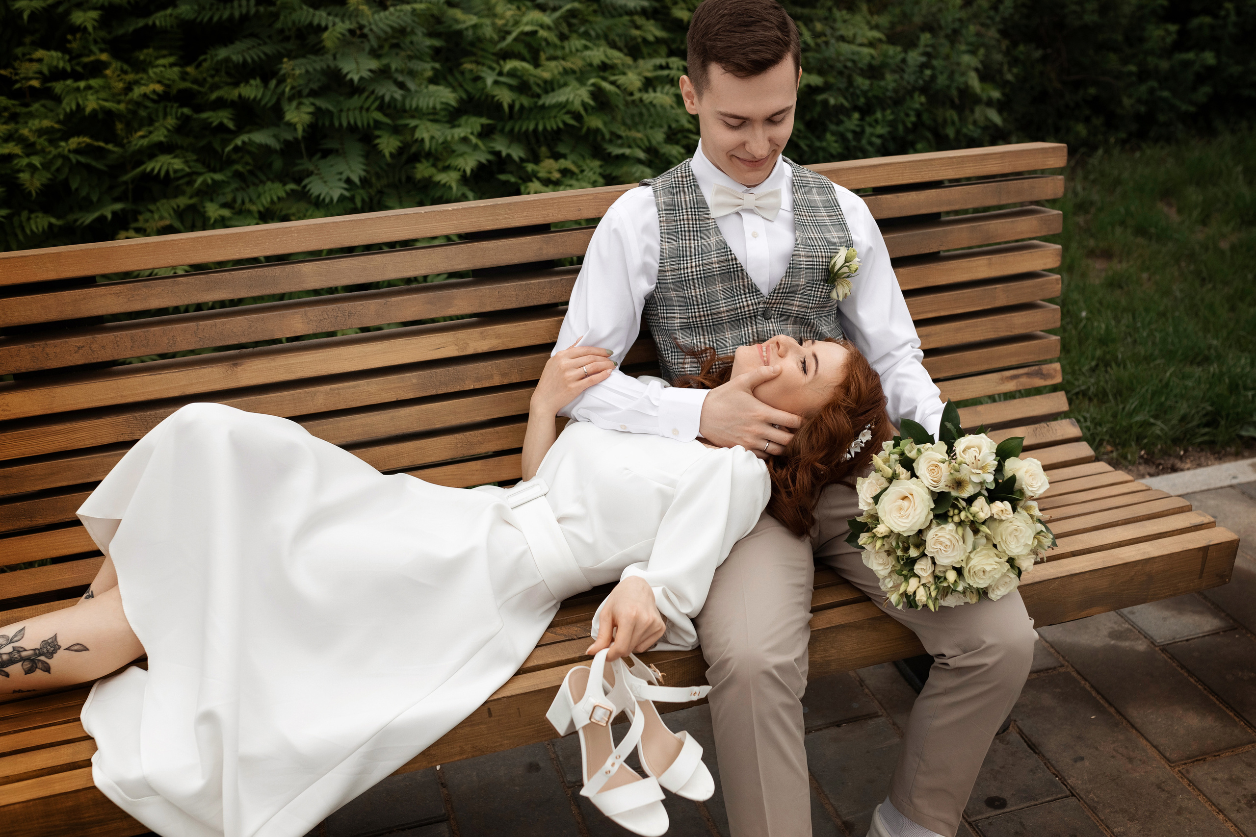 жених позирует с невестой на лавочке в парке
