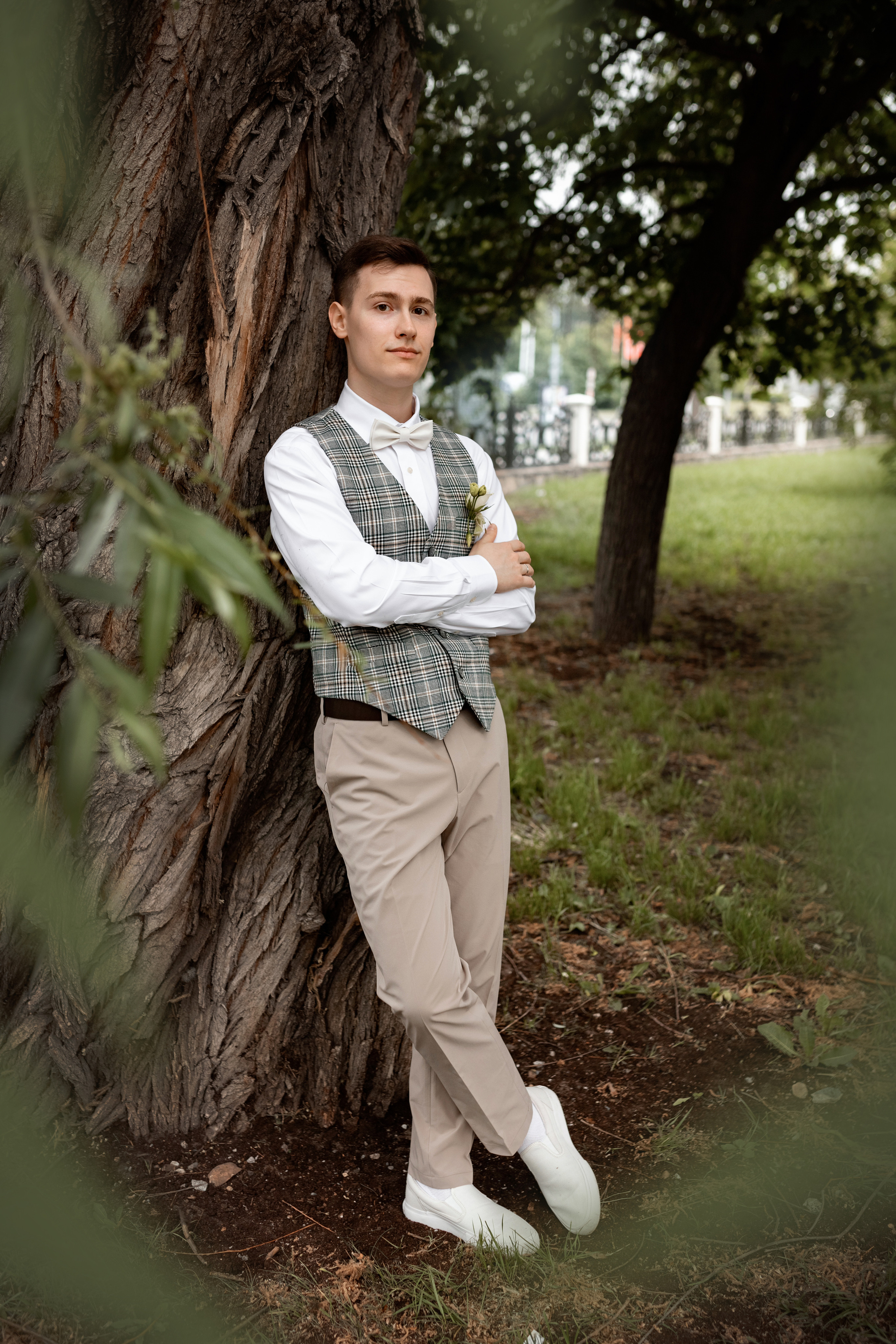 жених позирует у ствола широкого дерева