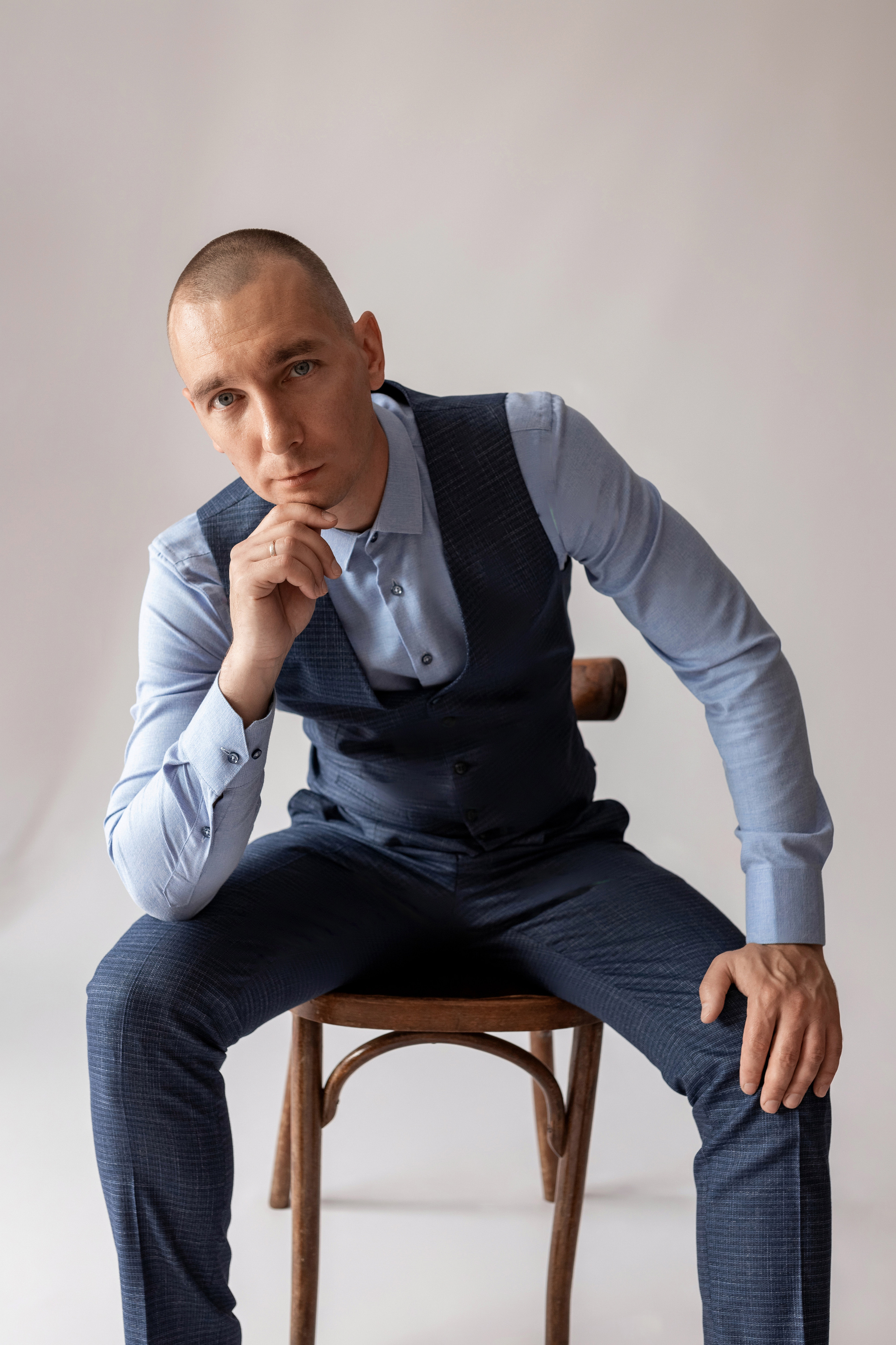 Индивидуальная мужская фотосессия в студии минимализм. на стуле. на белом фоне, на бежевом фоне. В классическом костюме тройка