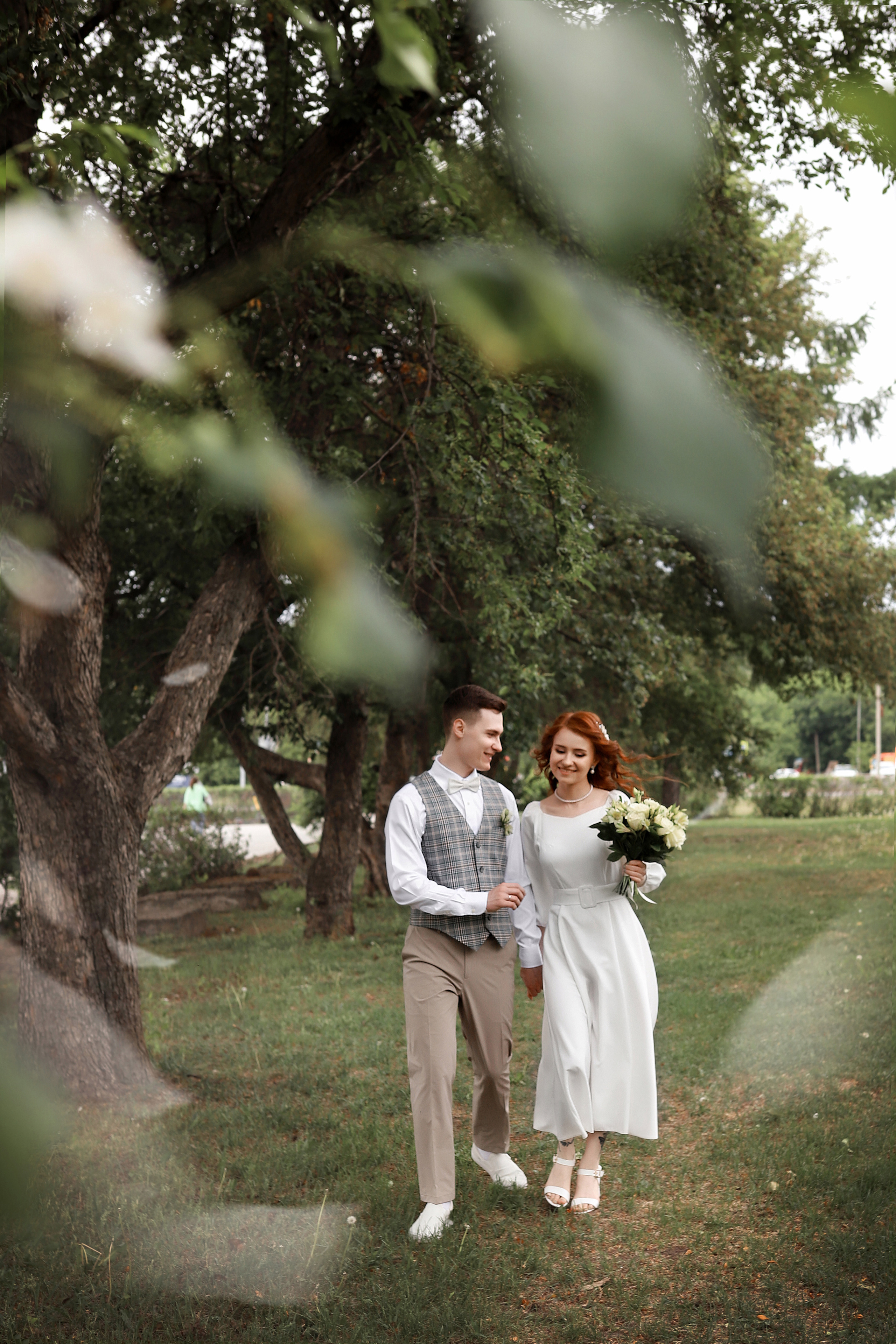жених и невеста бегут по яблоневой аллее
