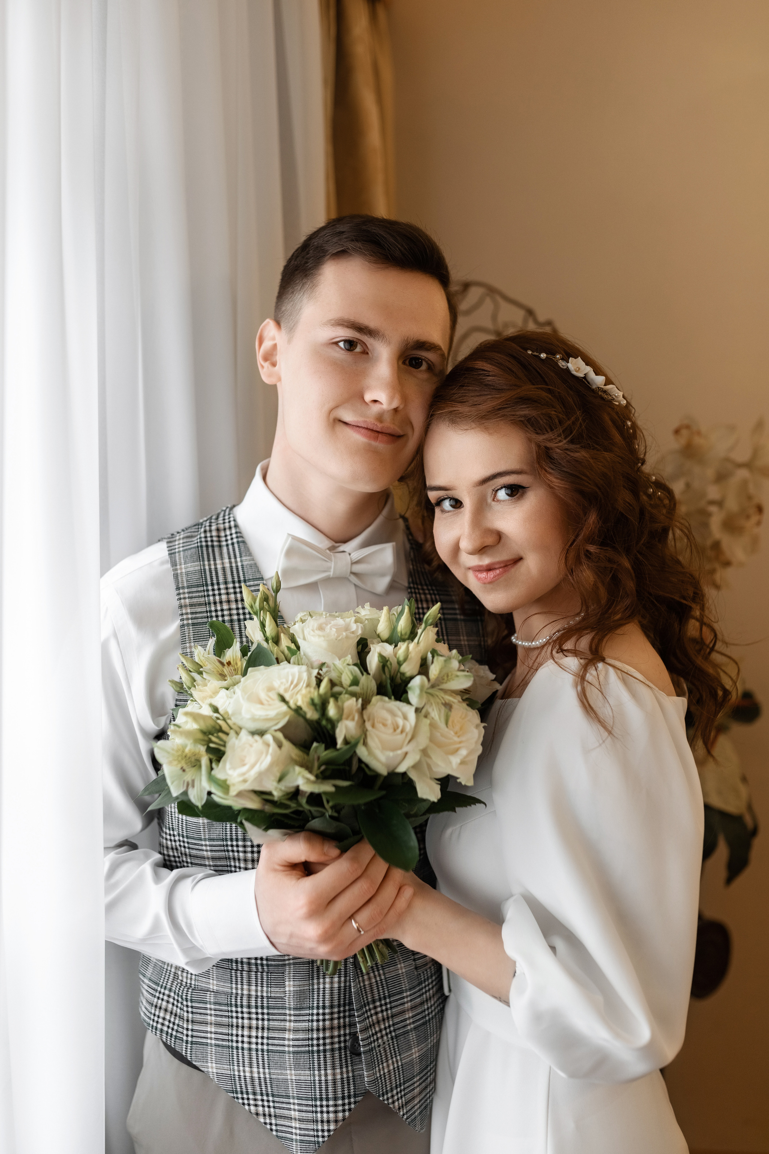 Молодожены стоят у окна в ЗАГСе