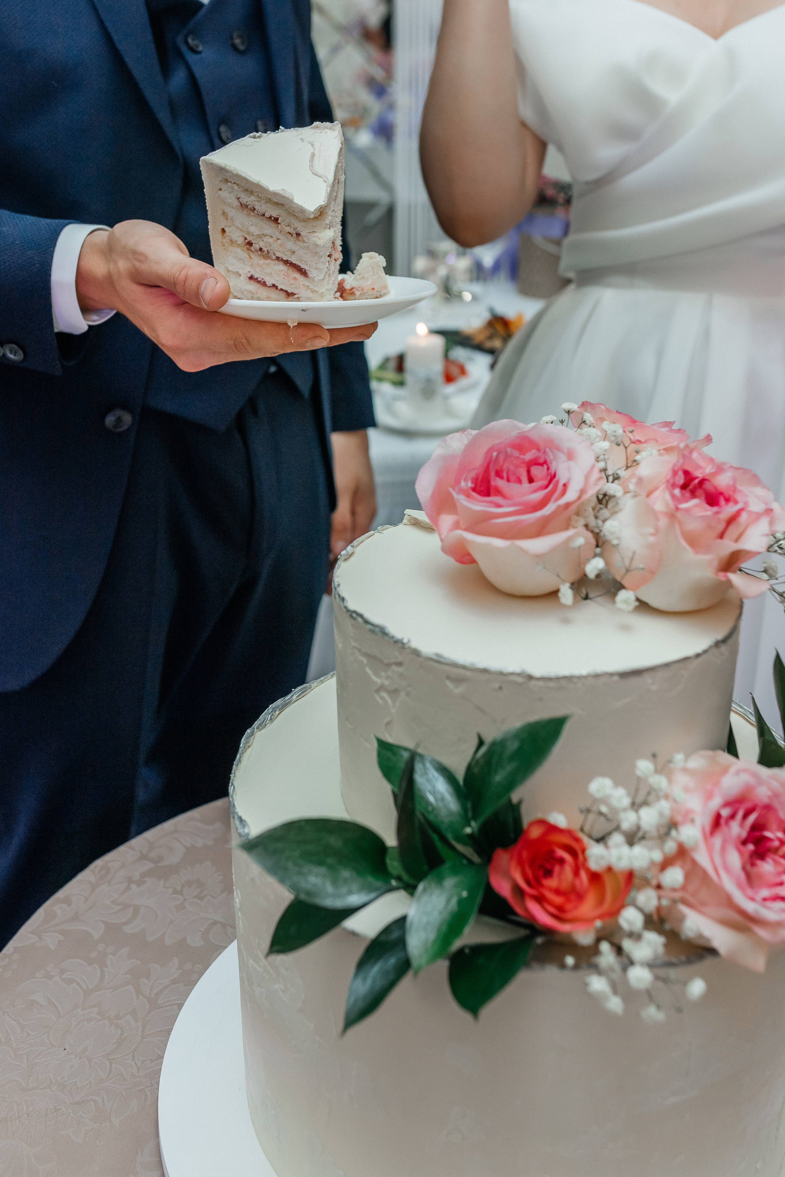 жених и невеста режут свадебный торт с живыми цветами