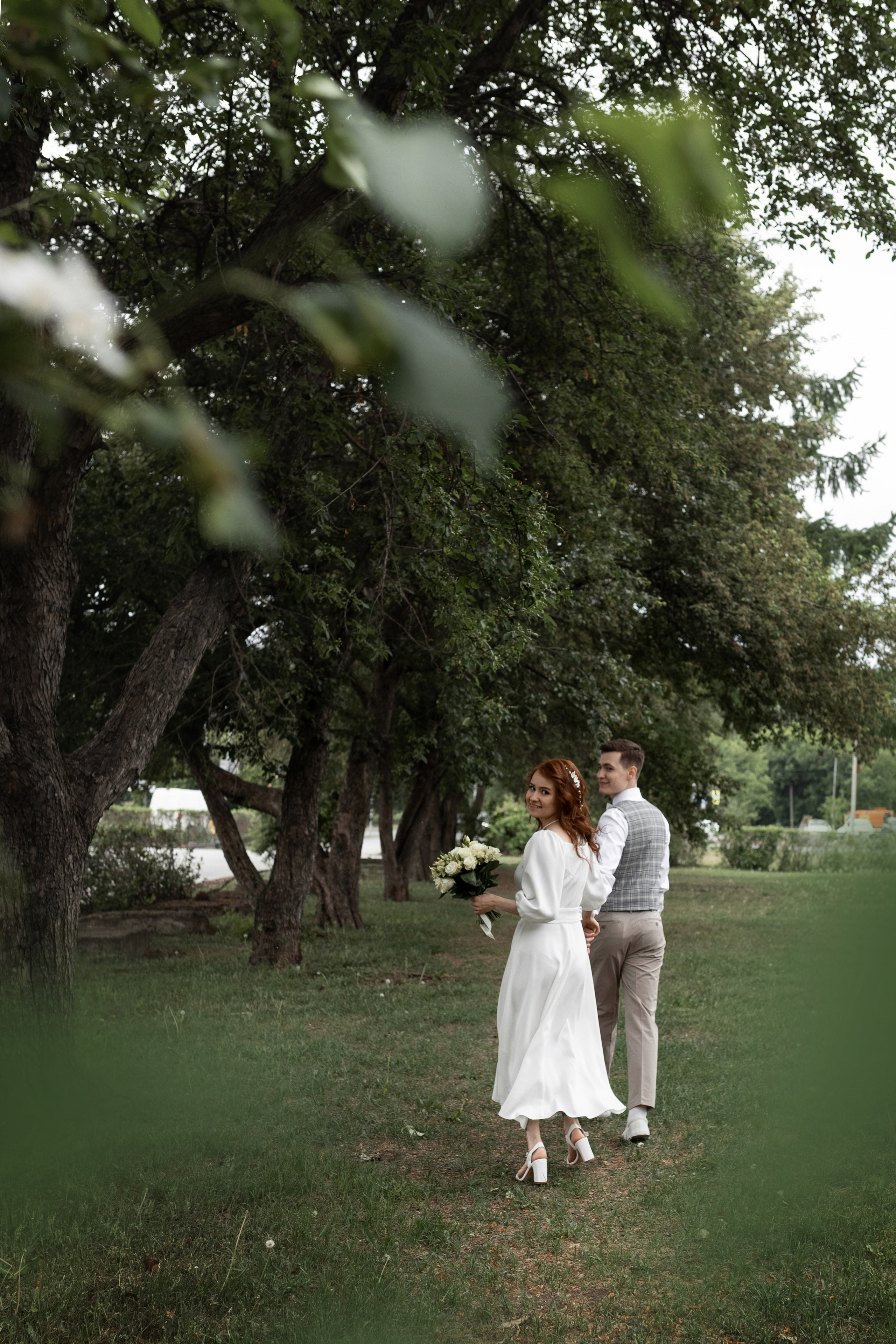 жених и невеста бегут по яблоневой аллее