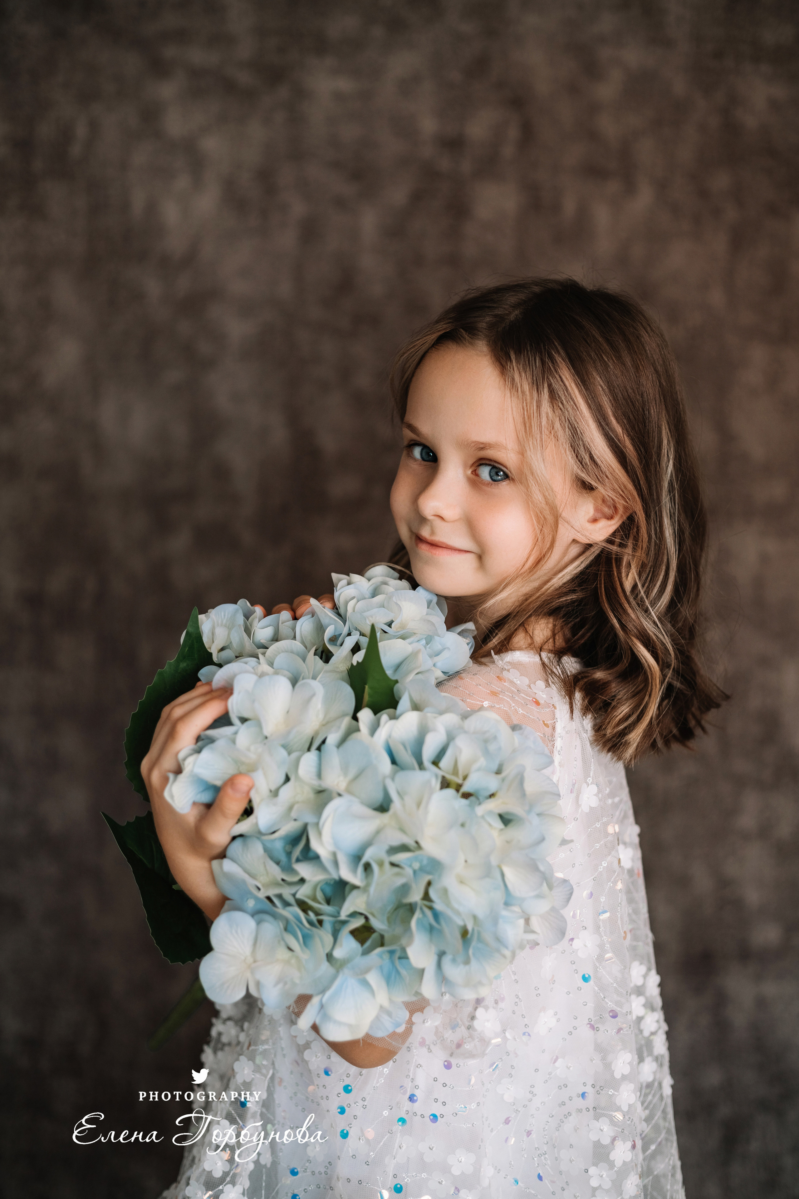 Фотосессия в садике Пермь фотограф Елена Гобунова Девочка в белом платье позирует на стуле с цветами Открытка для мамы. Детская фотосессия. Детский портрет в студии