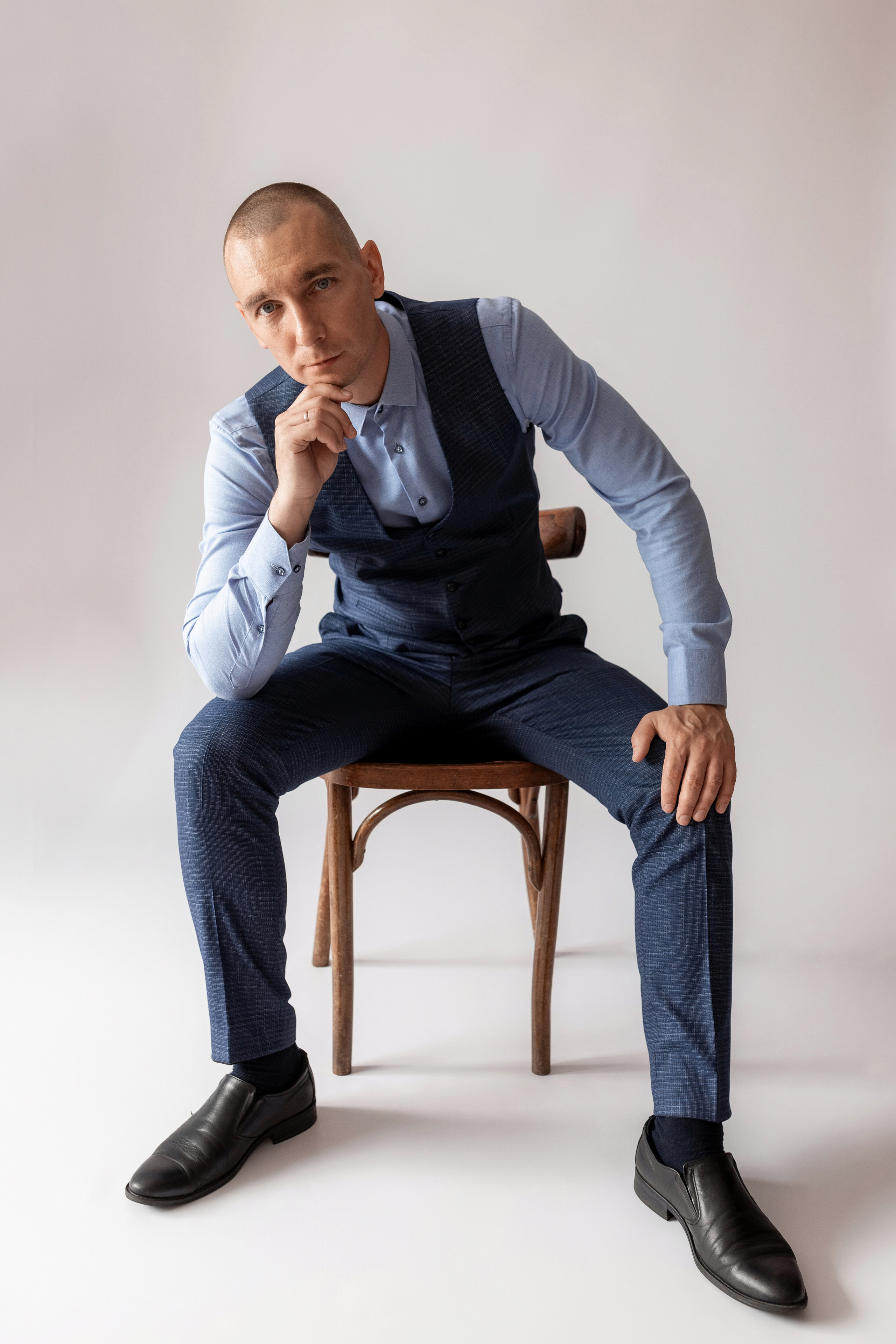 Индивидуальная мужская фотосессия в студии минимализм. на стуле. на белом фоне, на бежевом фоне. В классическом костюме тройка