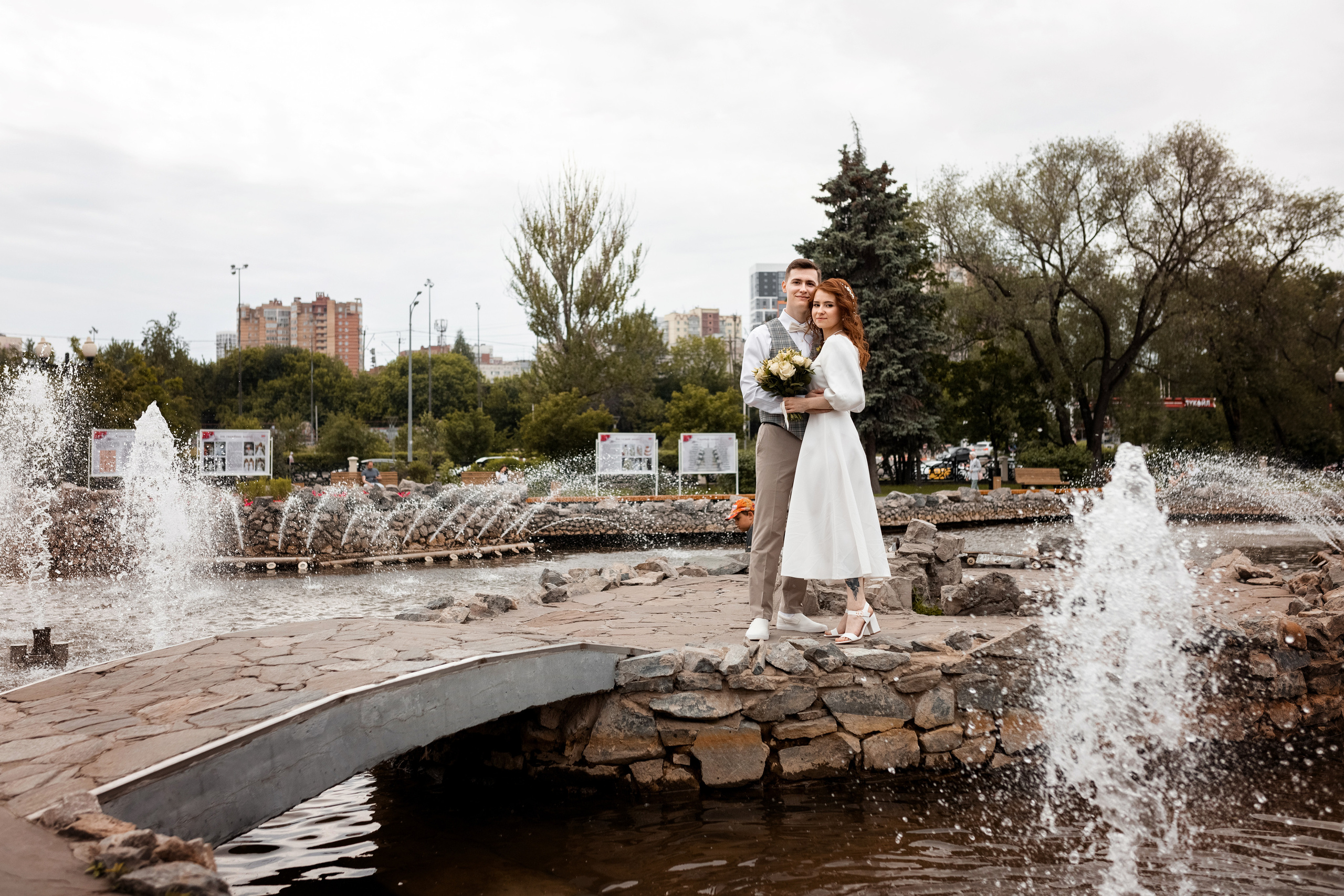 Молодожены на свадебной фото прогулке у фонтана
