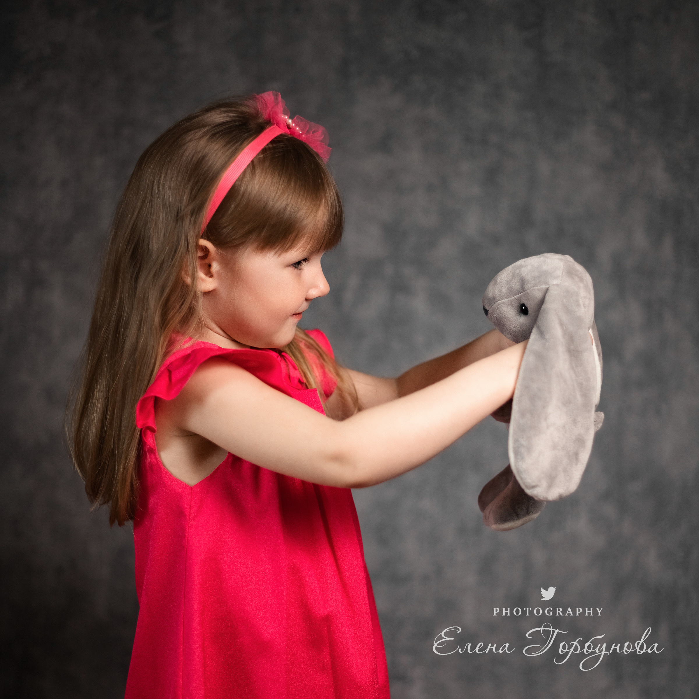 Детский портрет с игрушкой с эмоциями. Портрет в садике. Эмоции. Игра с волосами на фото. Девочка в розовом платье позирует на фоне в студии.