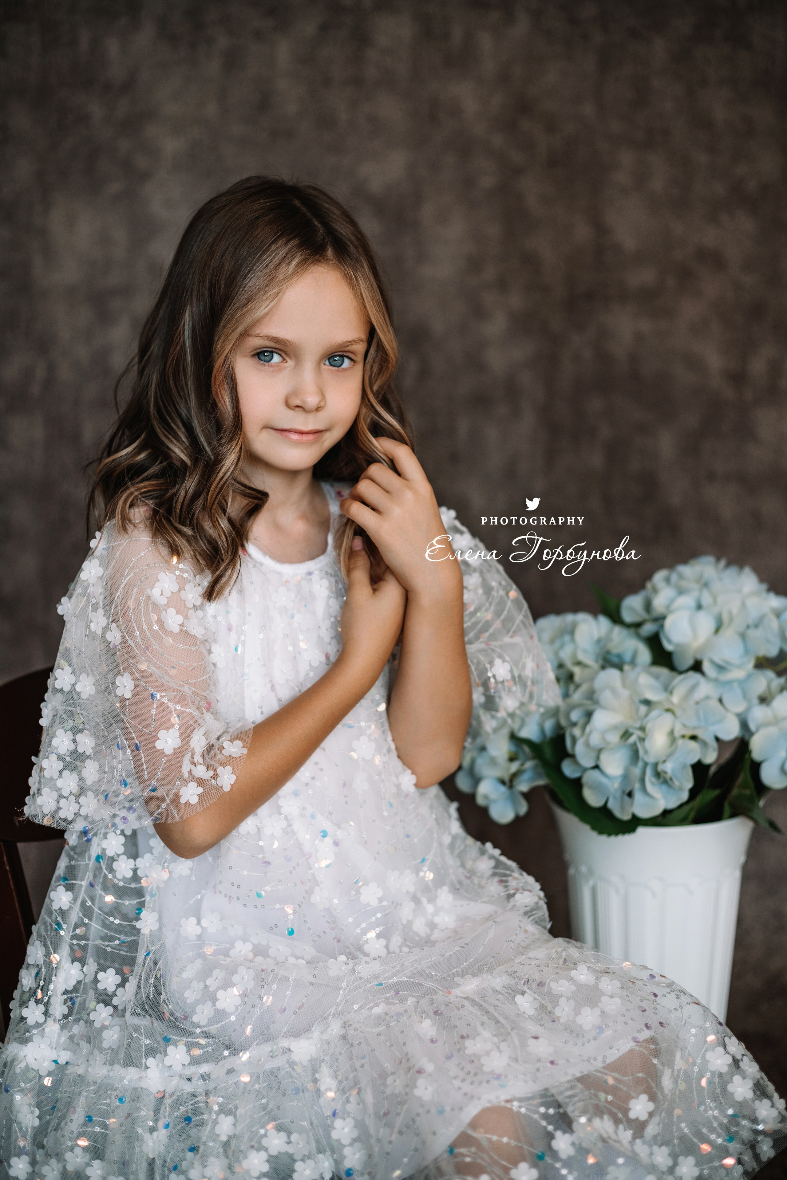 Фотосессия в садике Пермь фотограф Елена Гобунова Девочка в белом платье позирует на стуле с цветами Открытка для мамы. Детская фотосессия. Детский портрет в студии