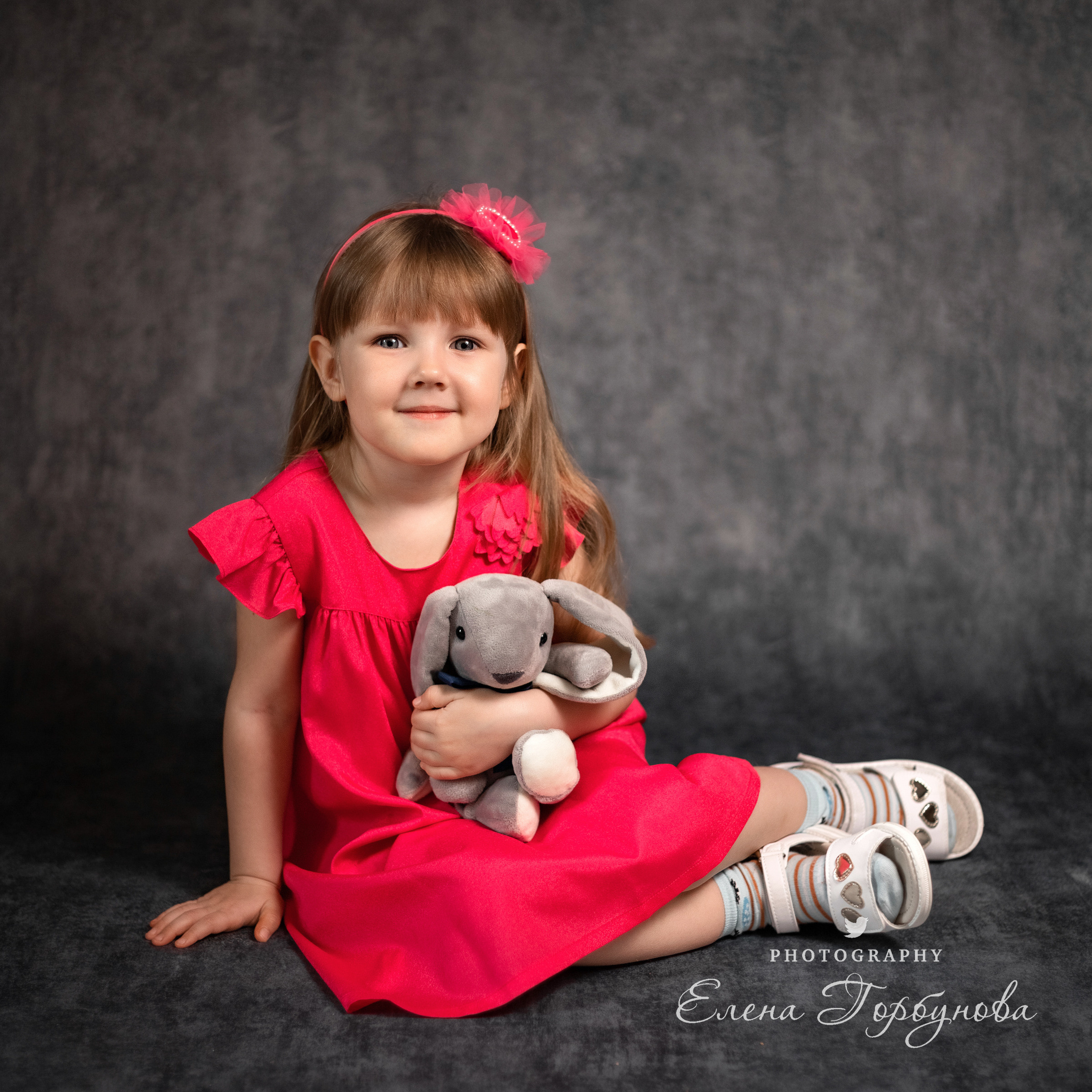 Детский портрет с игрушкой с эмоциями. Портрет в садике. Эмоции. Игра с волосами на фото. Девочка в розовом платье позирует на фоне в студии.