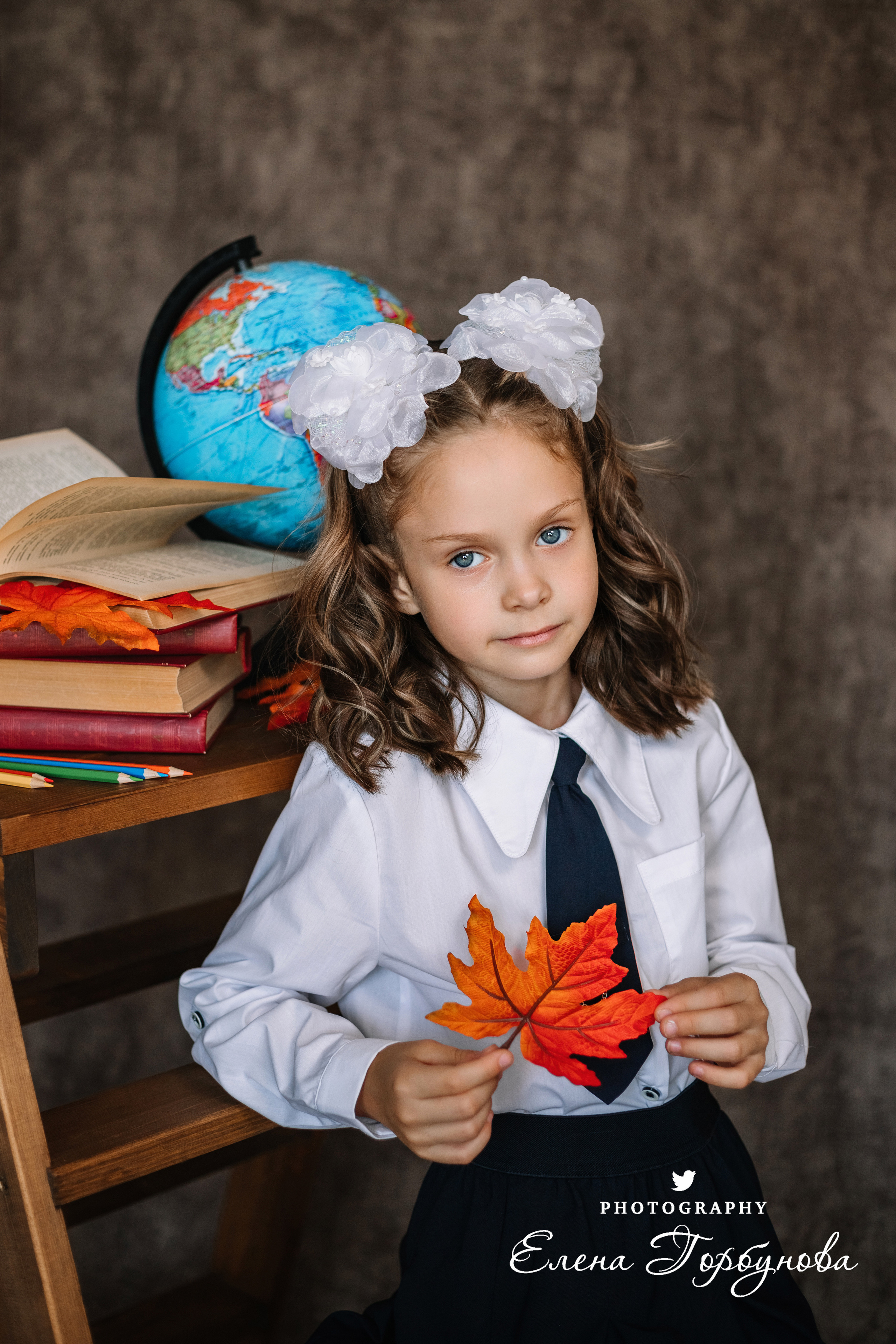 Фотограф Елена Горбунова Пермь. школьный портрет. фотосессия на 1 сентября. девочка в школьной форме с глобусом и книжками, с осенними листьями. Листья клена на портрете. школьный портрет в студии на фото. художественный портрет. школьный фотограф.