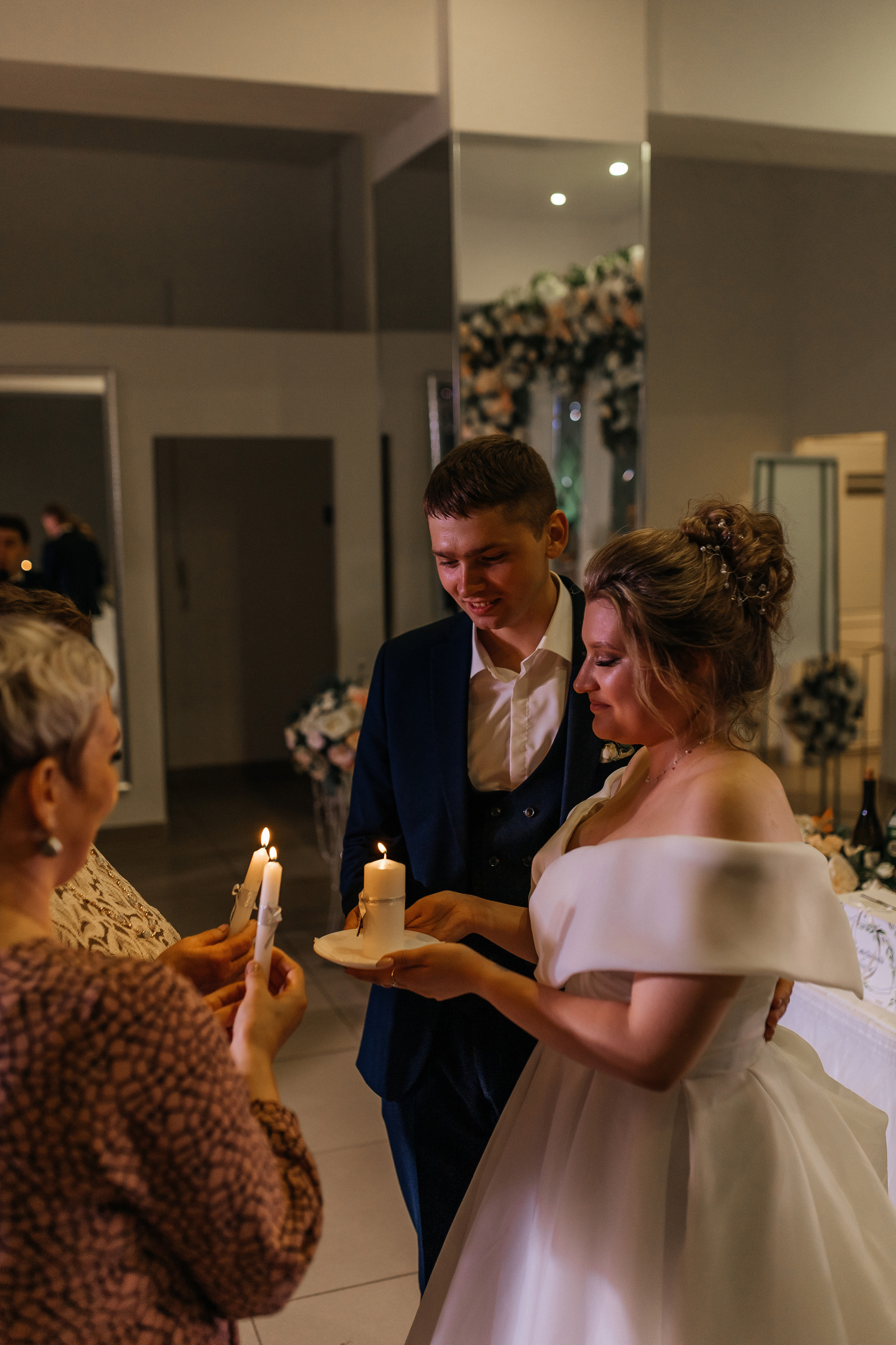 Родители жениха и невесты зажигают свечи. Репортажное фото с банкета