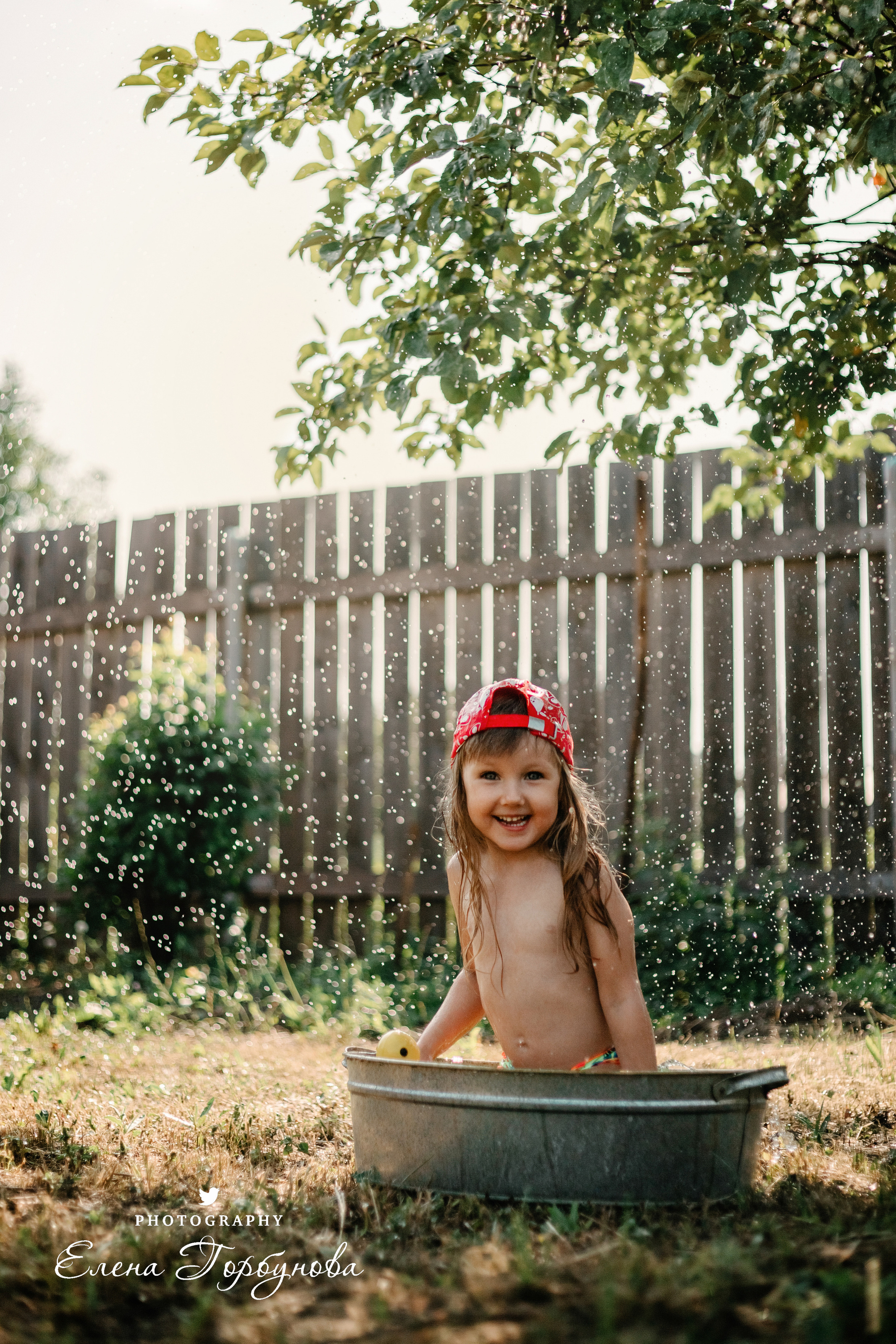Детская фотосессия на природе на даче летом в тазике под яблоней с брызгами воды, с фонтаном