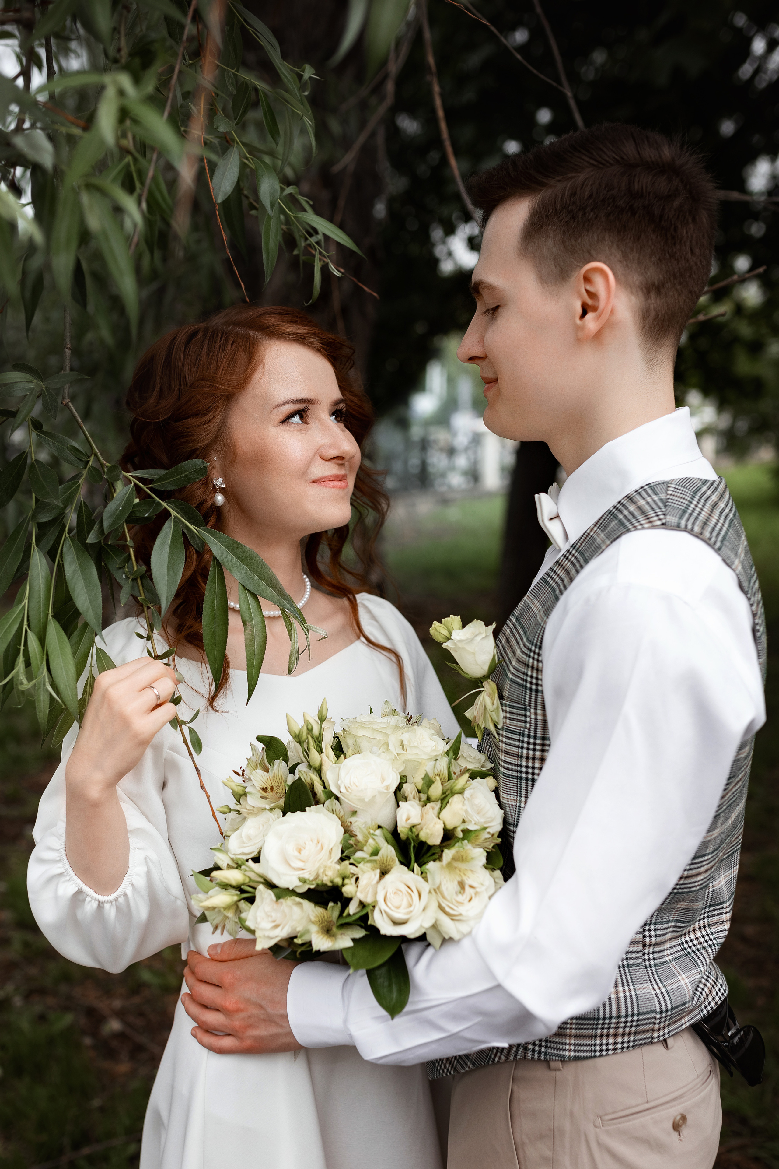 невеста позирует с букетом в листьях дерева