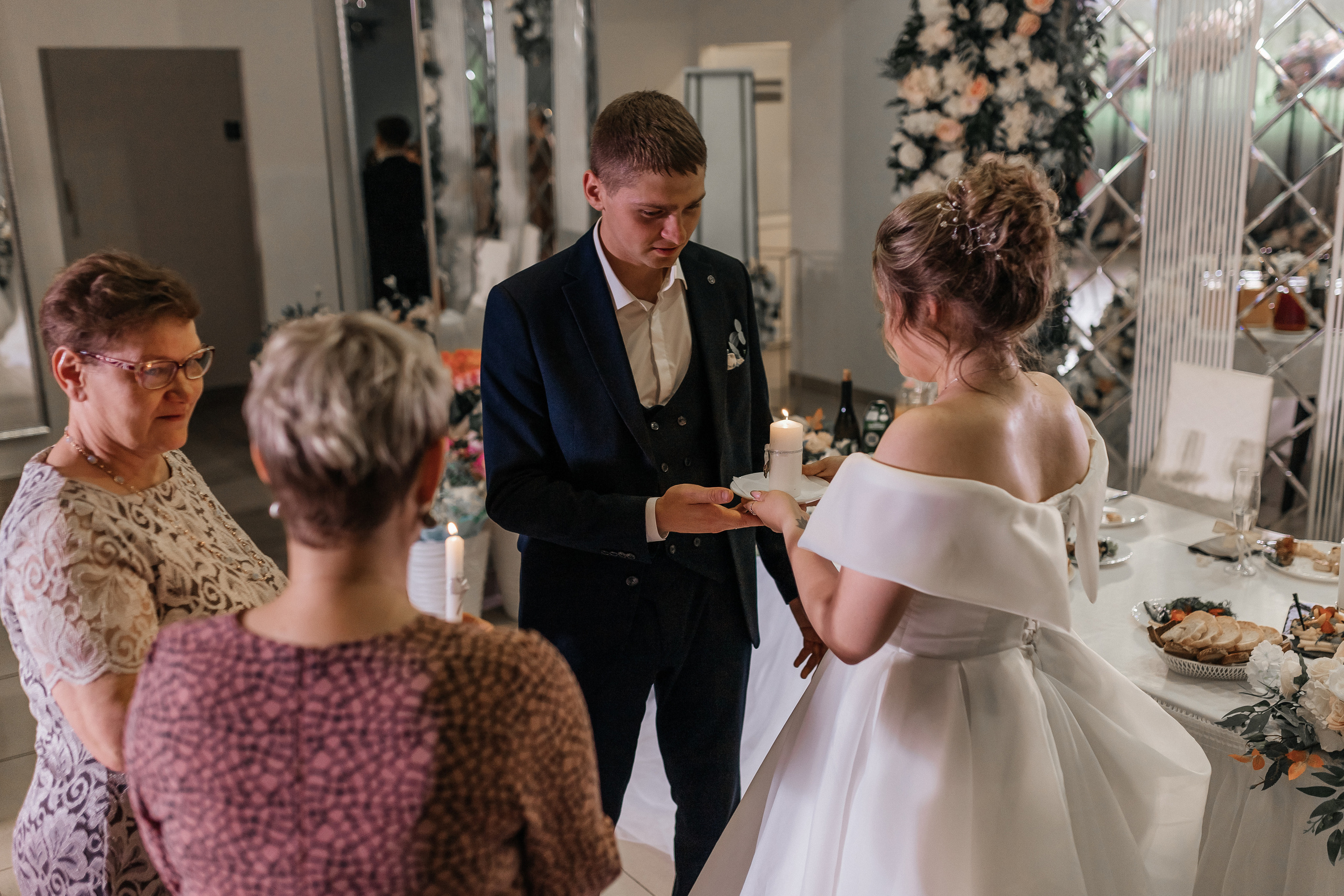 Родители жениха и невесты зажигают свечи. Репортажное фото с банкета