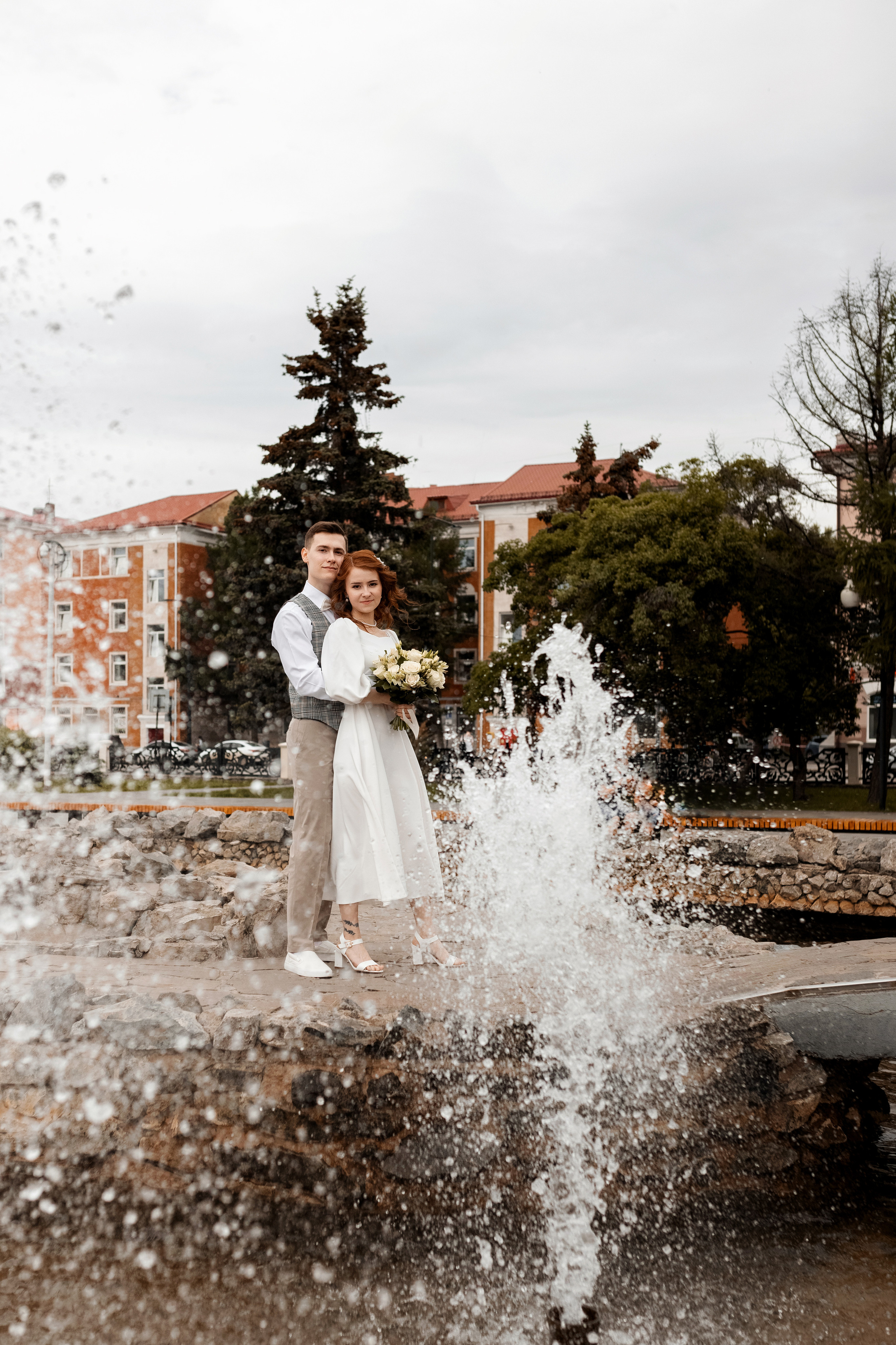 Молодожены на свадебной фото прогулке у фонтана