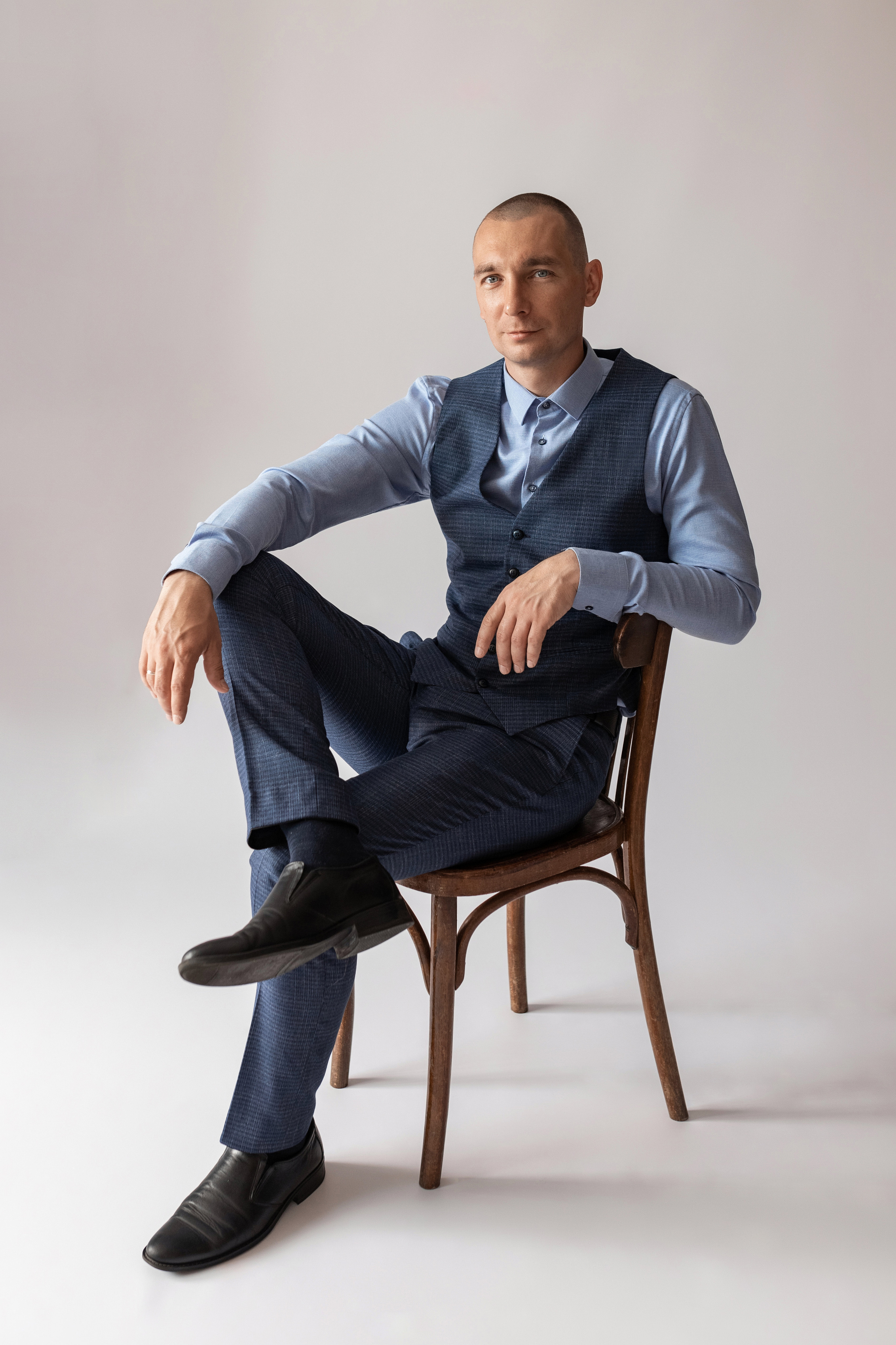 Индивидуальная мужская фотосессия в студии минимализм. на стуле. на белом фоне, на бежевом фоне. В классическом костюме тройка