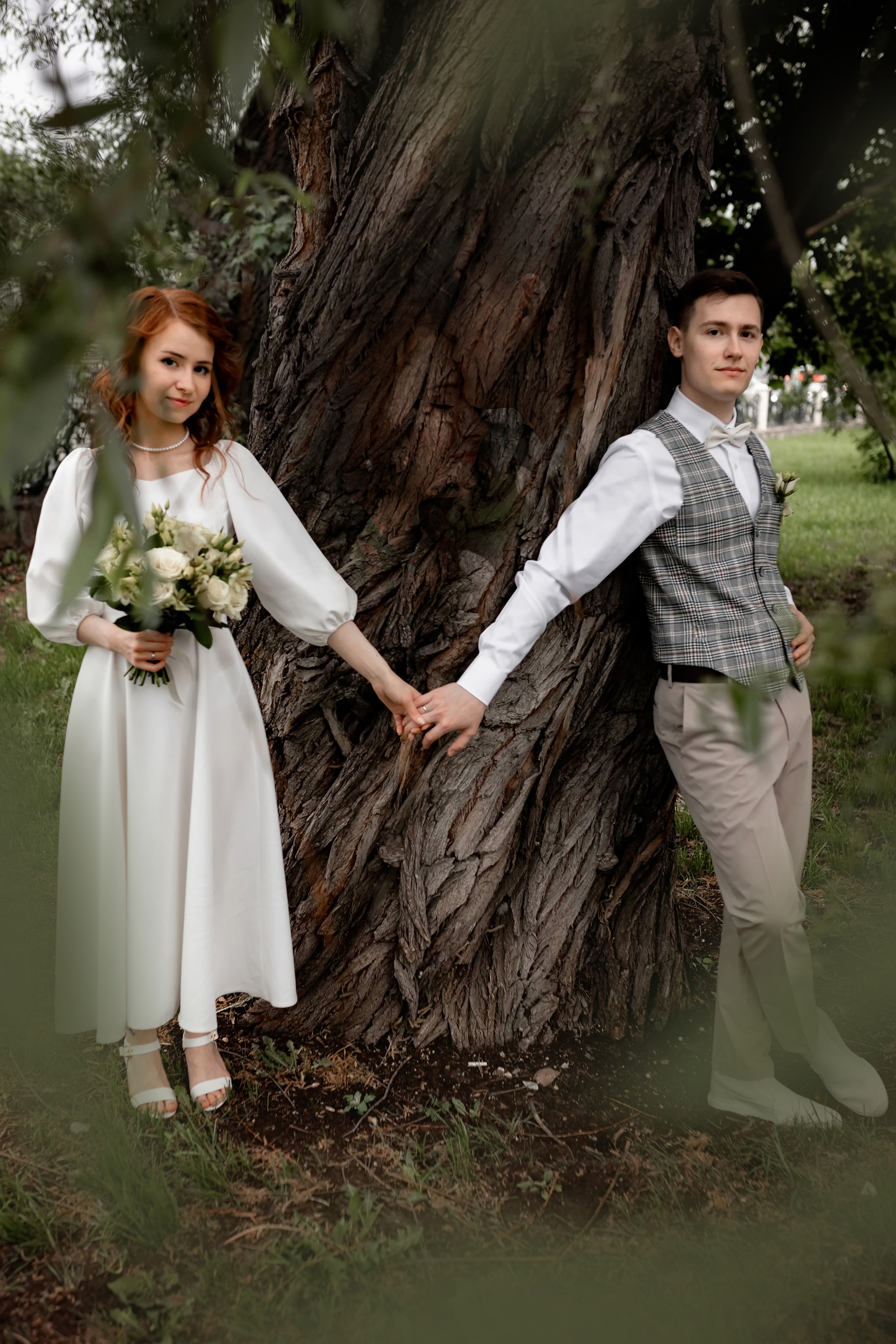 жених позирует у ствола широкого дерева