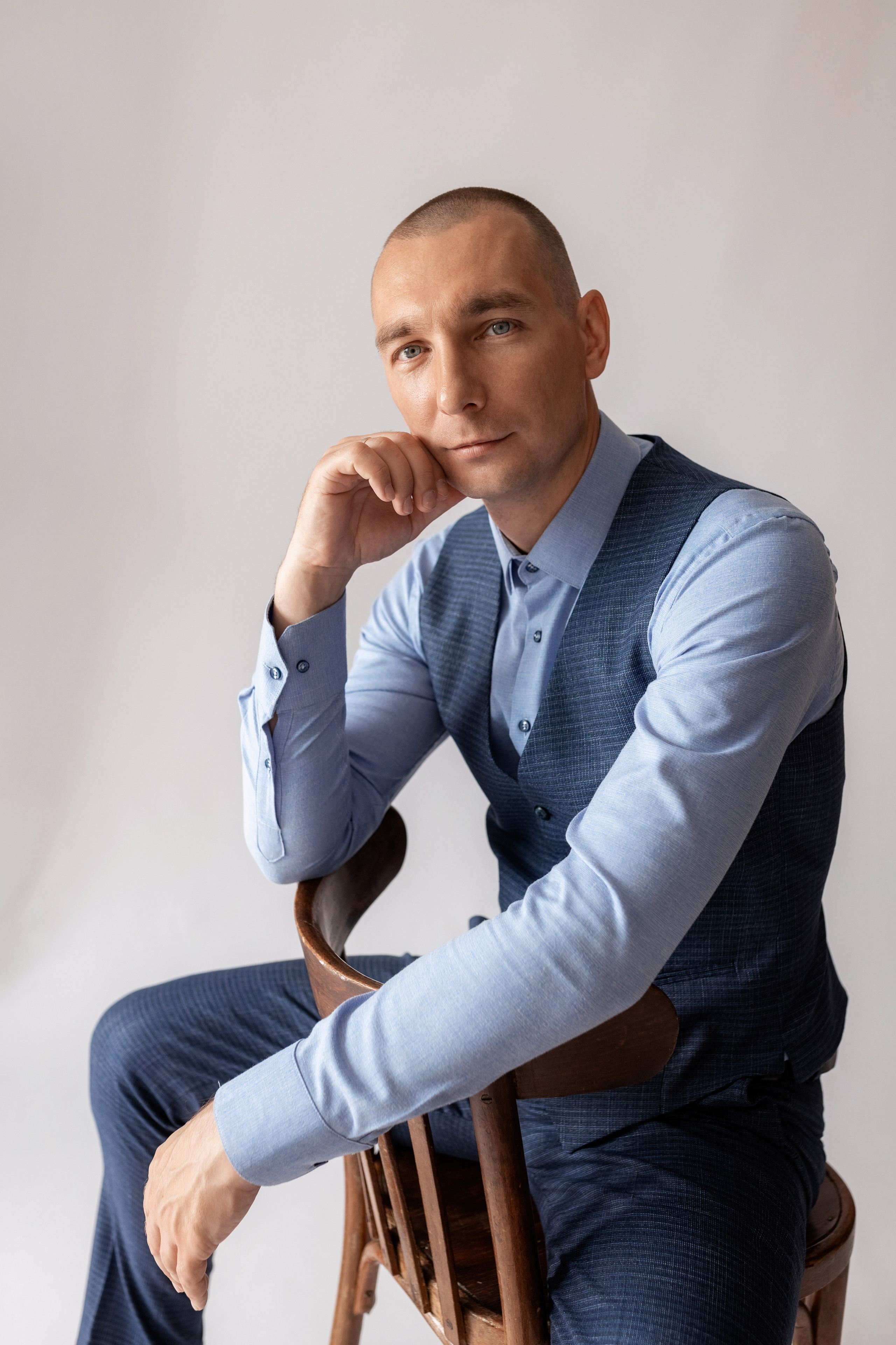 Индивидуальная мужская фотосессия в студии минимализм. на стуле. на белом фоне, на бежевом фоне. В классическом костюме тройка