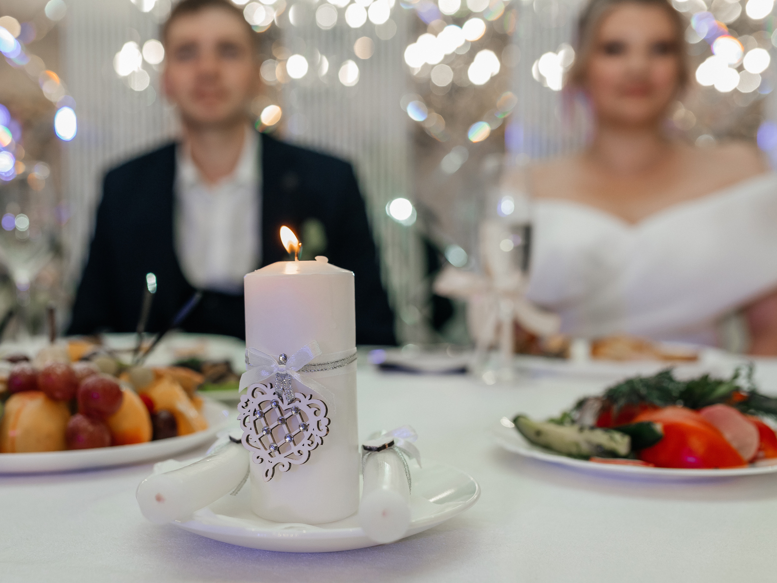 Родители жениха и невесты зажигают свечи. Репортажное фото с банкета