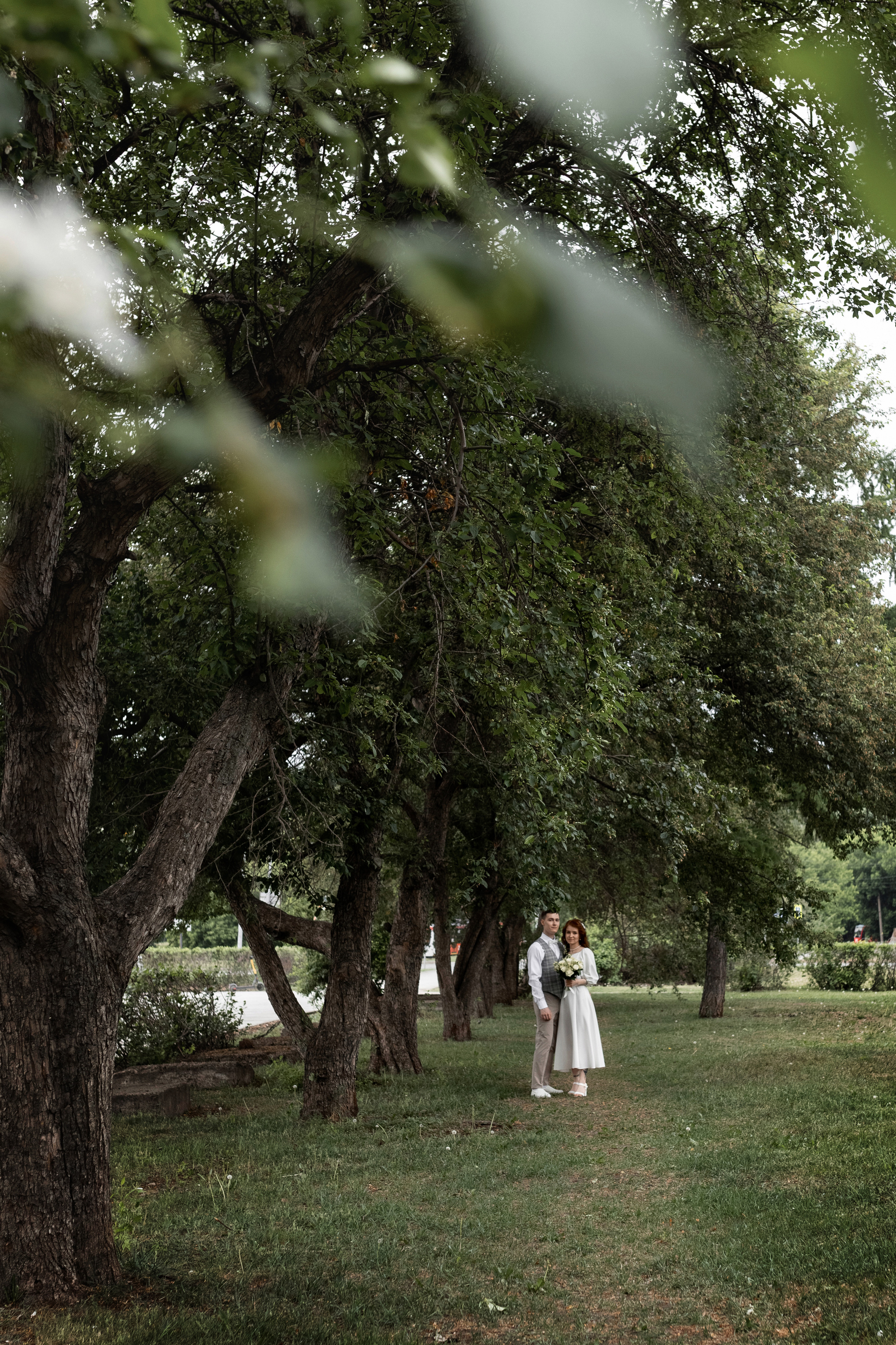 жених и невеста бегут по яблоневой аллее