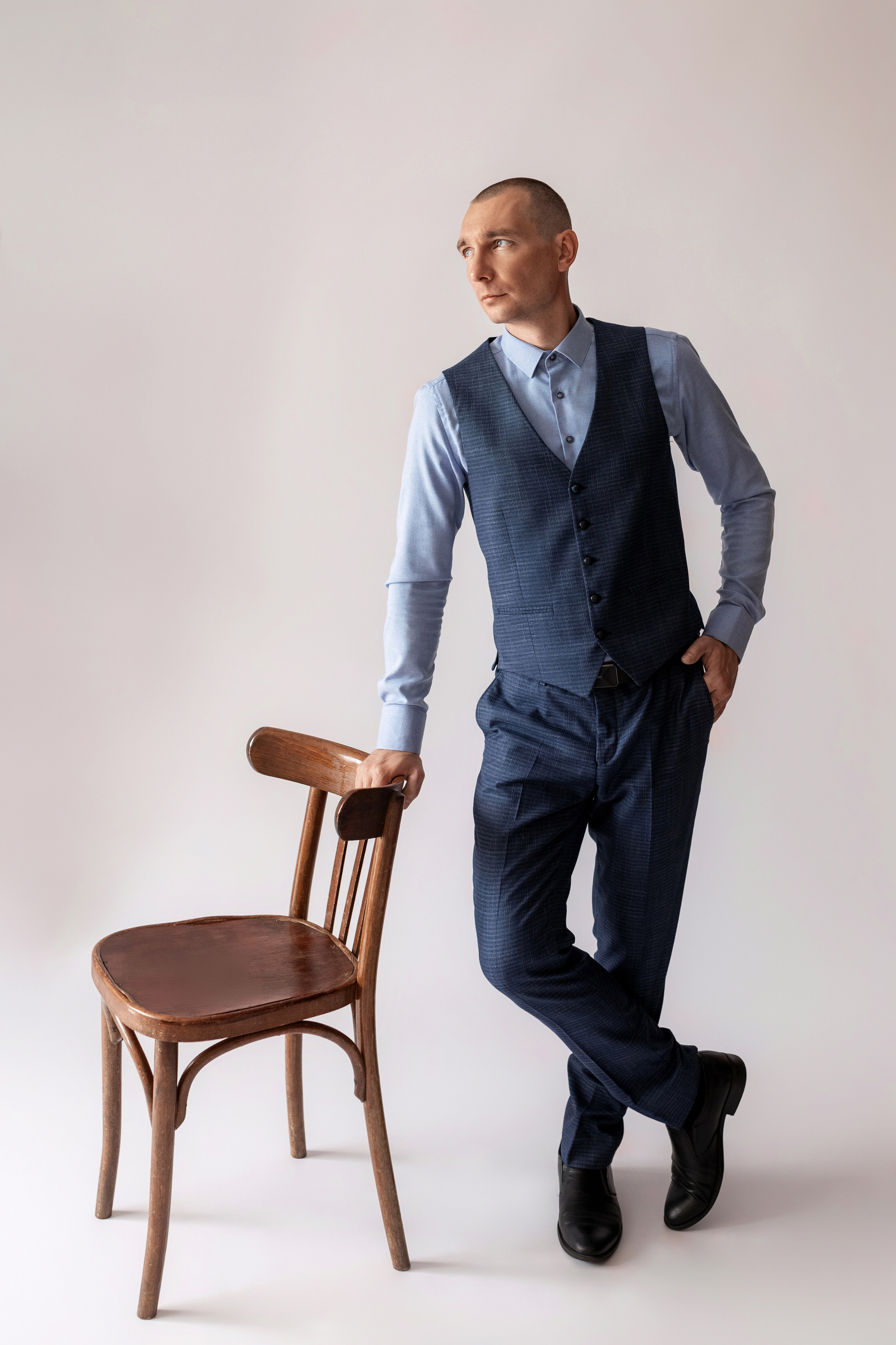 Индивидуальная мужская фотосессия в студии минимализм. на стуле. на белом фоне, на бежевом фоне. В классическом костюме тройка