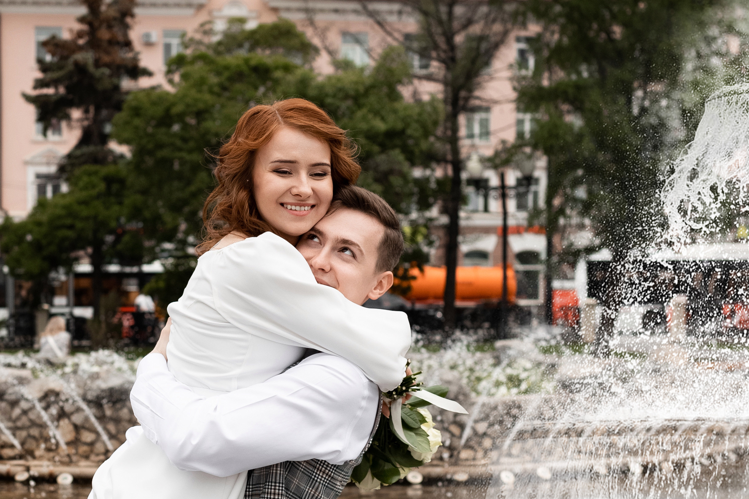 Невеста и жених кружатся в брызгах фонтана с букетом