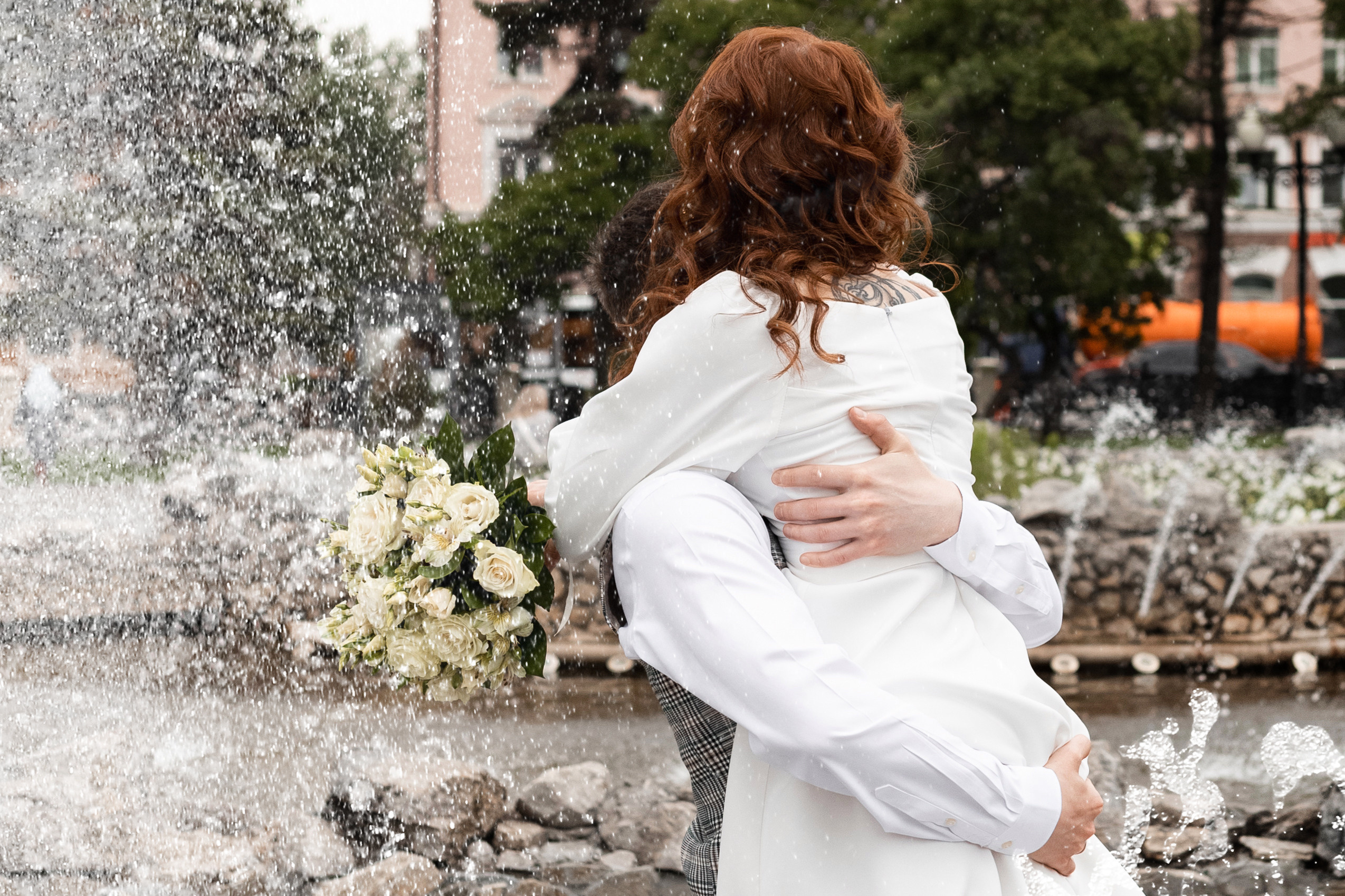 Невеста и жених кружатся в брызгах фонтана с букетом