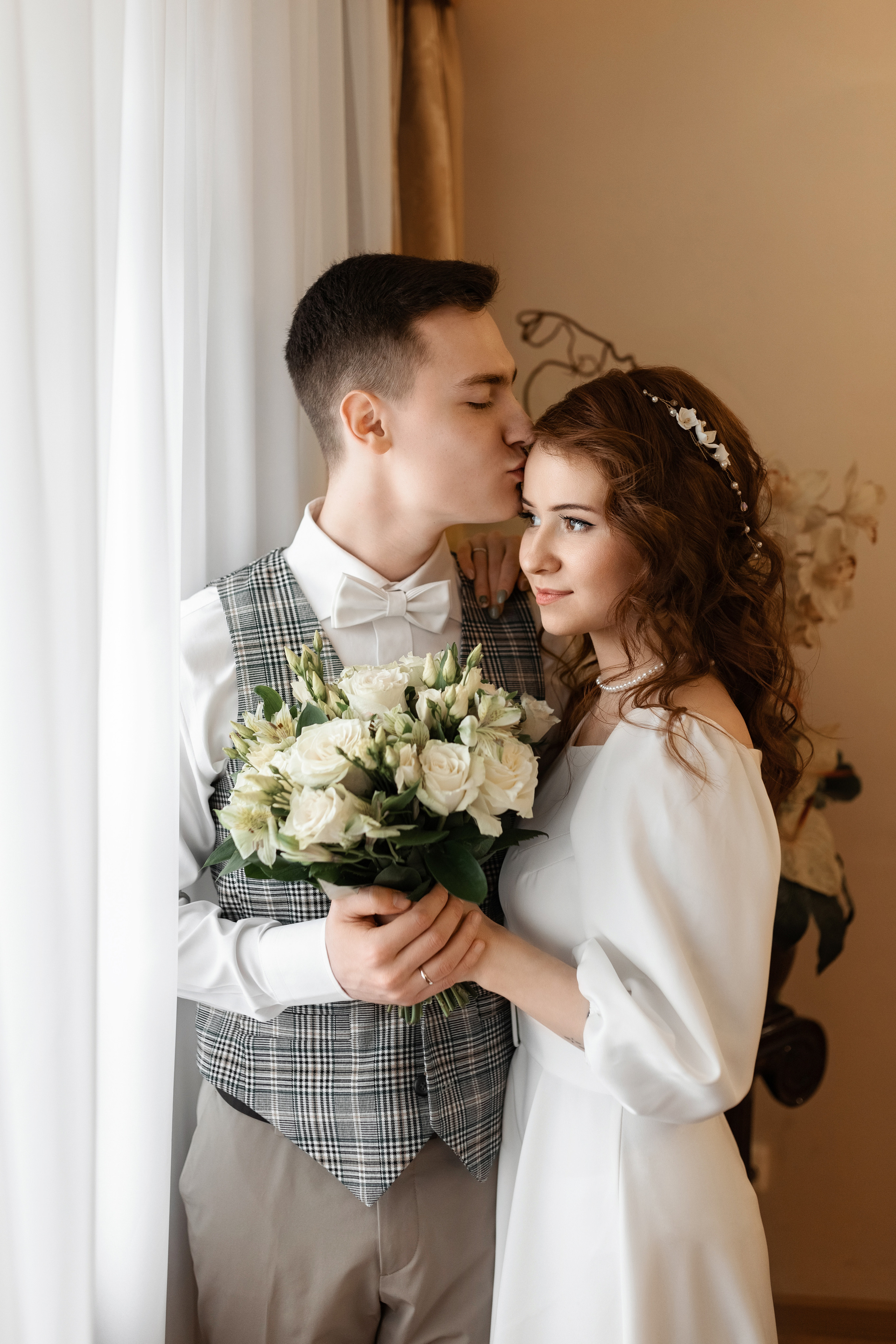 Молодожены стоят у окна в ЗАГСе