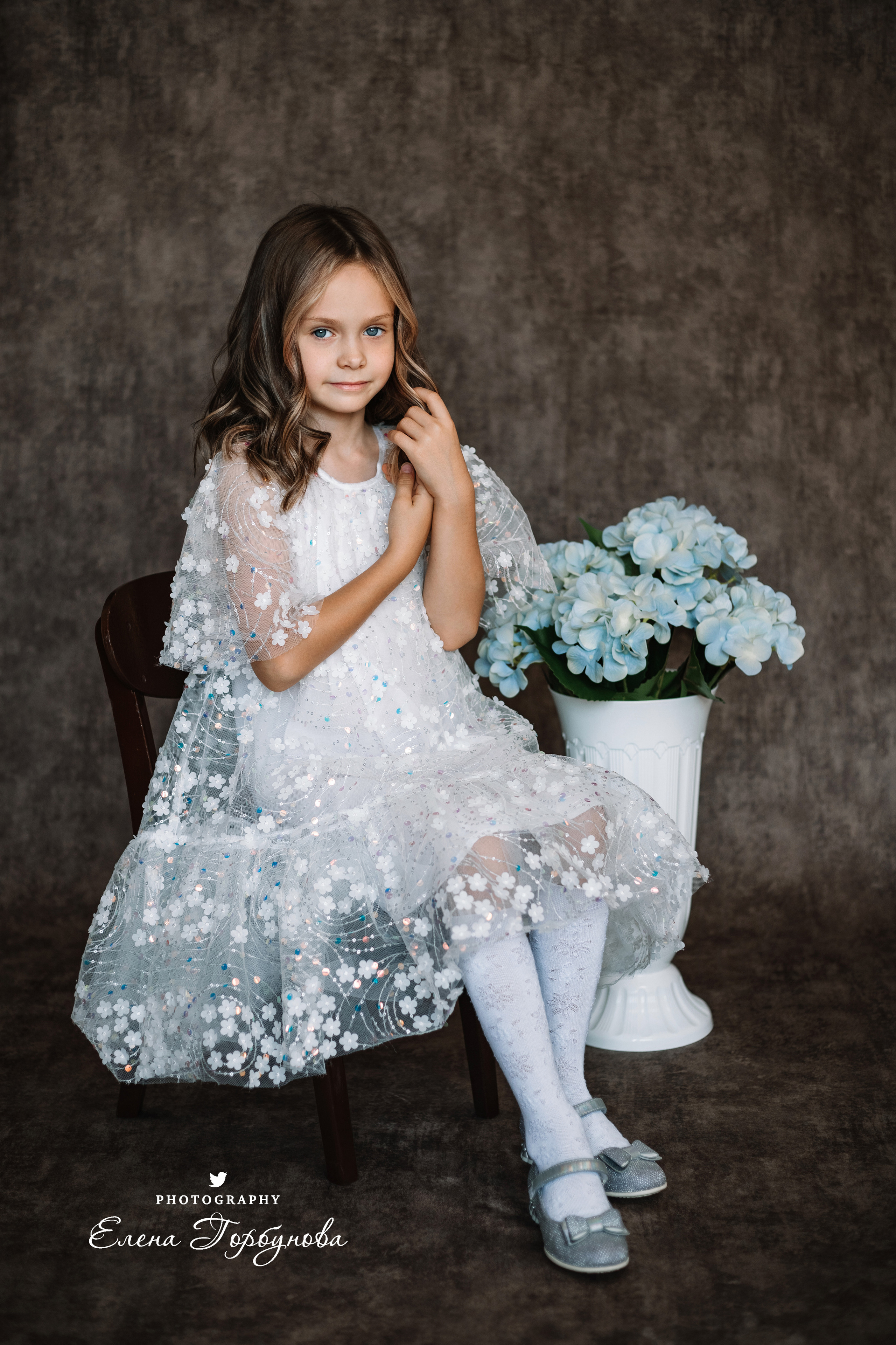 Фотосессия в садике Пермь фотограф Елена Гобунова Девочка в белом платье позирует на стуле с цветами Открытка для мамы. Детская фотосессия. Детский портрет в студии
