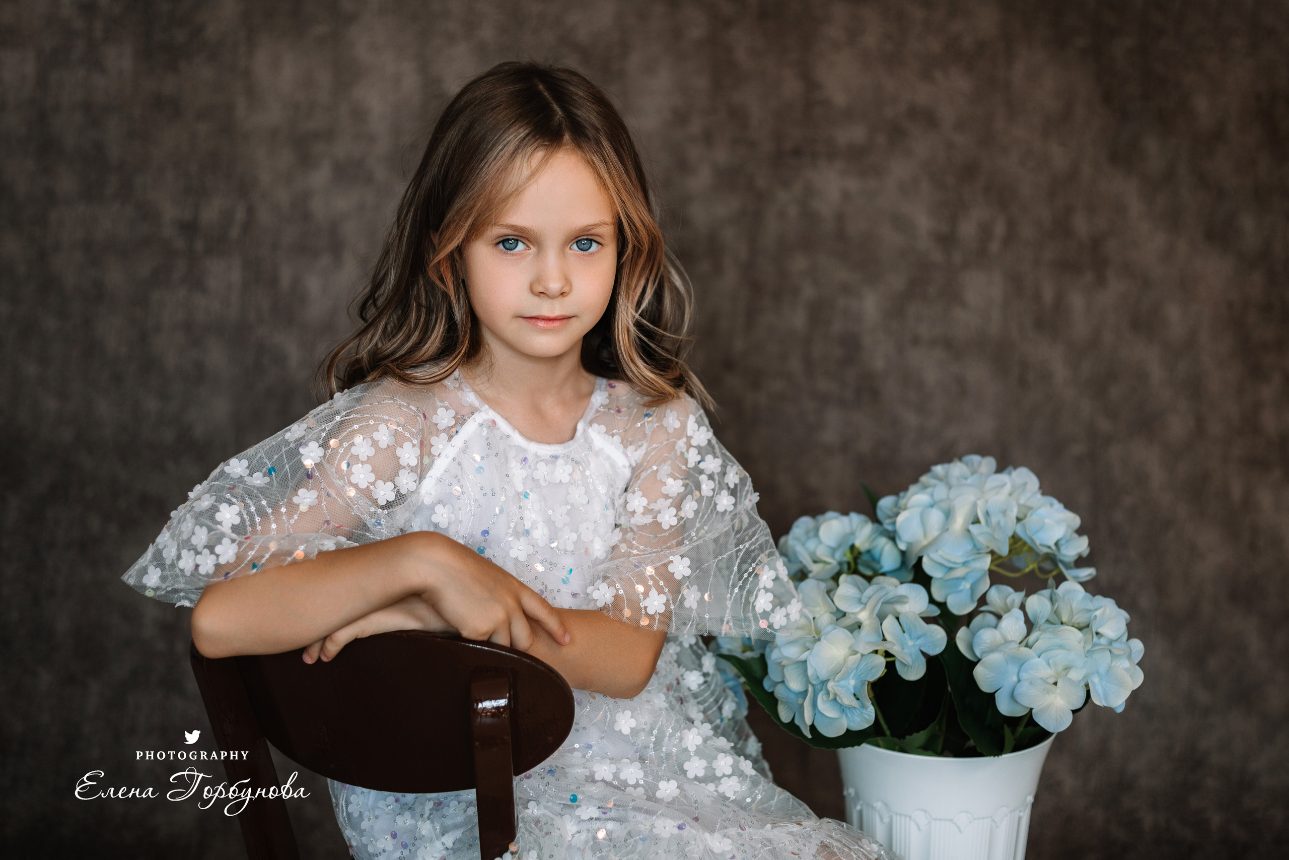 Фотосессия в садике Пермь фотограф Елена Гобунова Девочка в белом платье позирует на стуле с цветами Открытка для мамы. Детская фотосессия. Детский портрет в студии