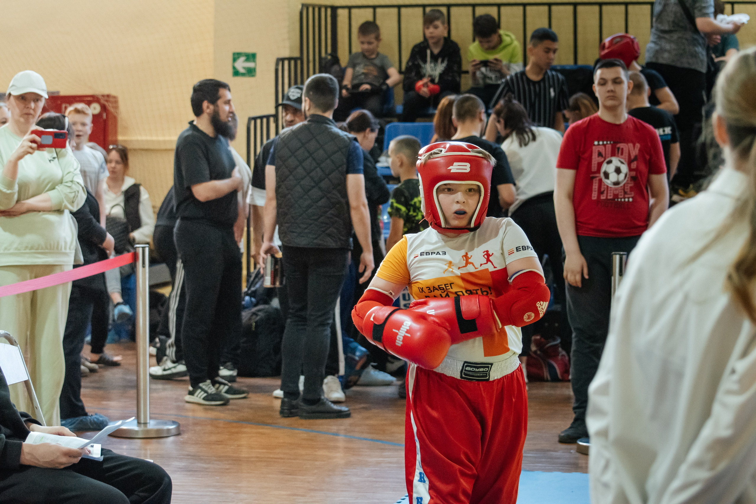 Мальчик выходит на ринг, надевая перчатки