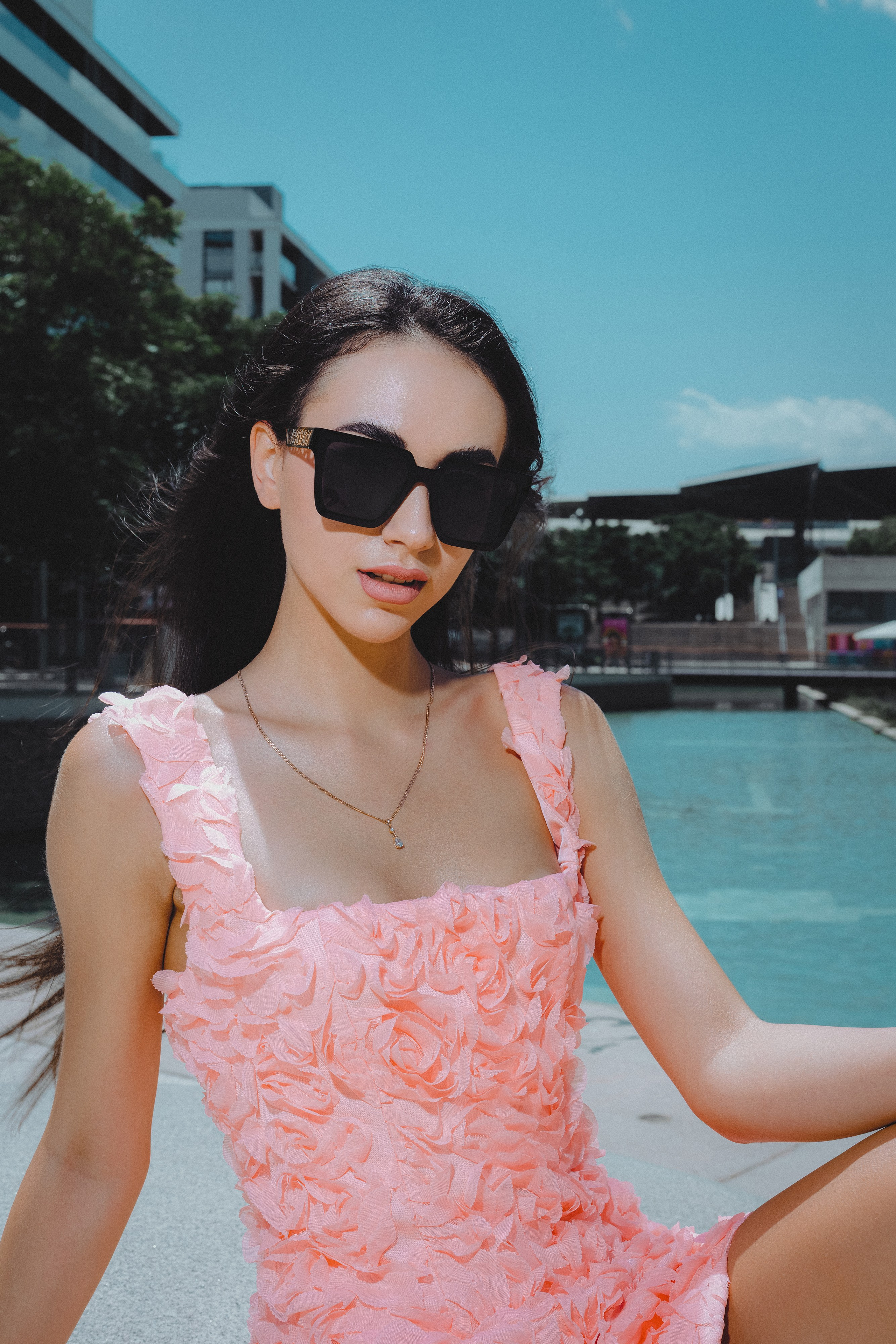 Elegant young woman in a soft pink dress walking through the streets of Barcelona.