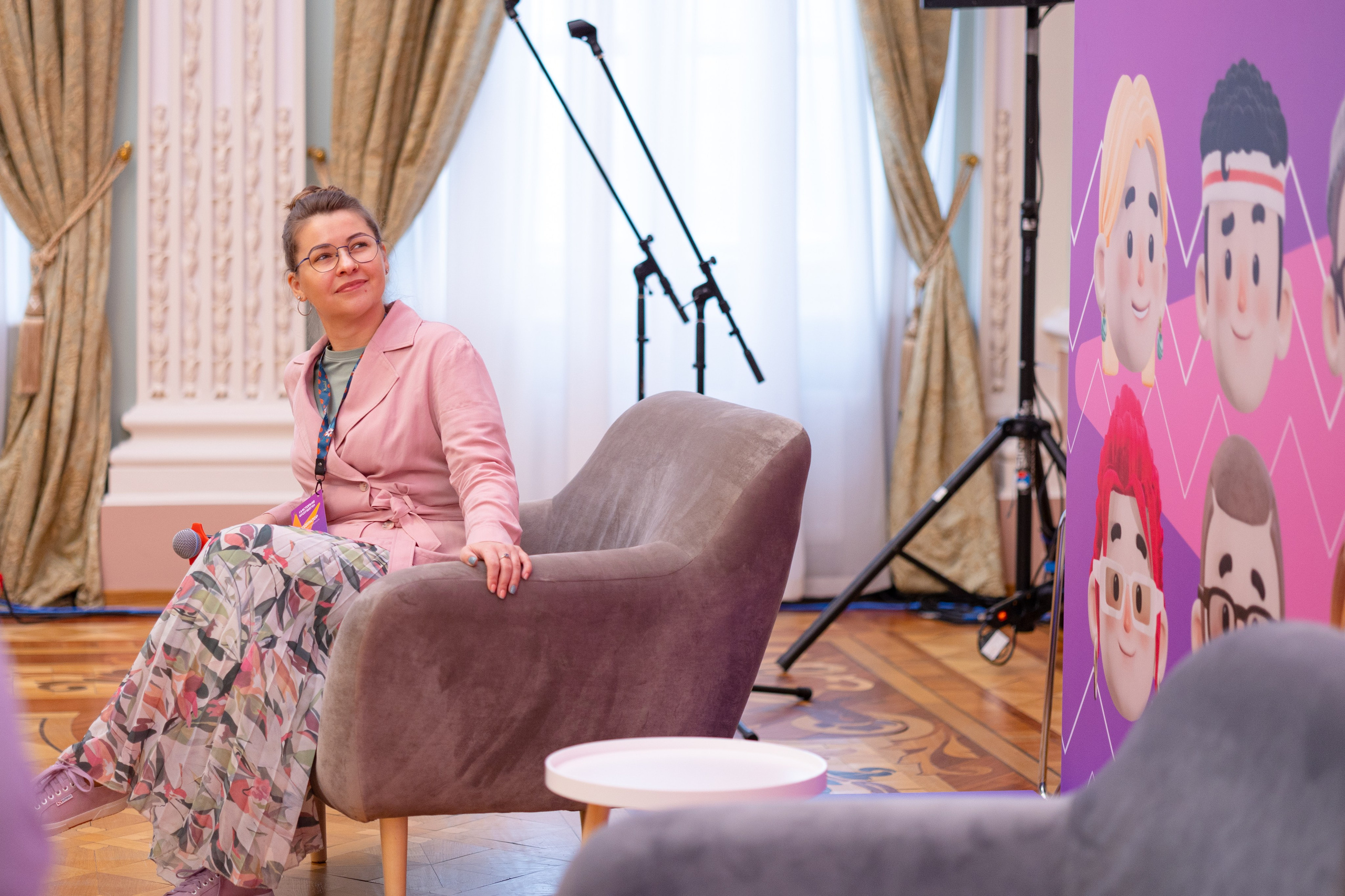 Девушка в длинном платье сидит в кресле.