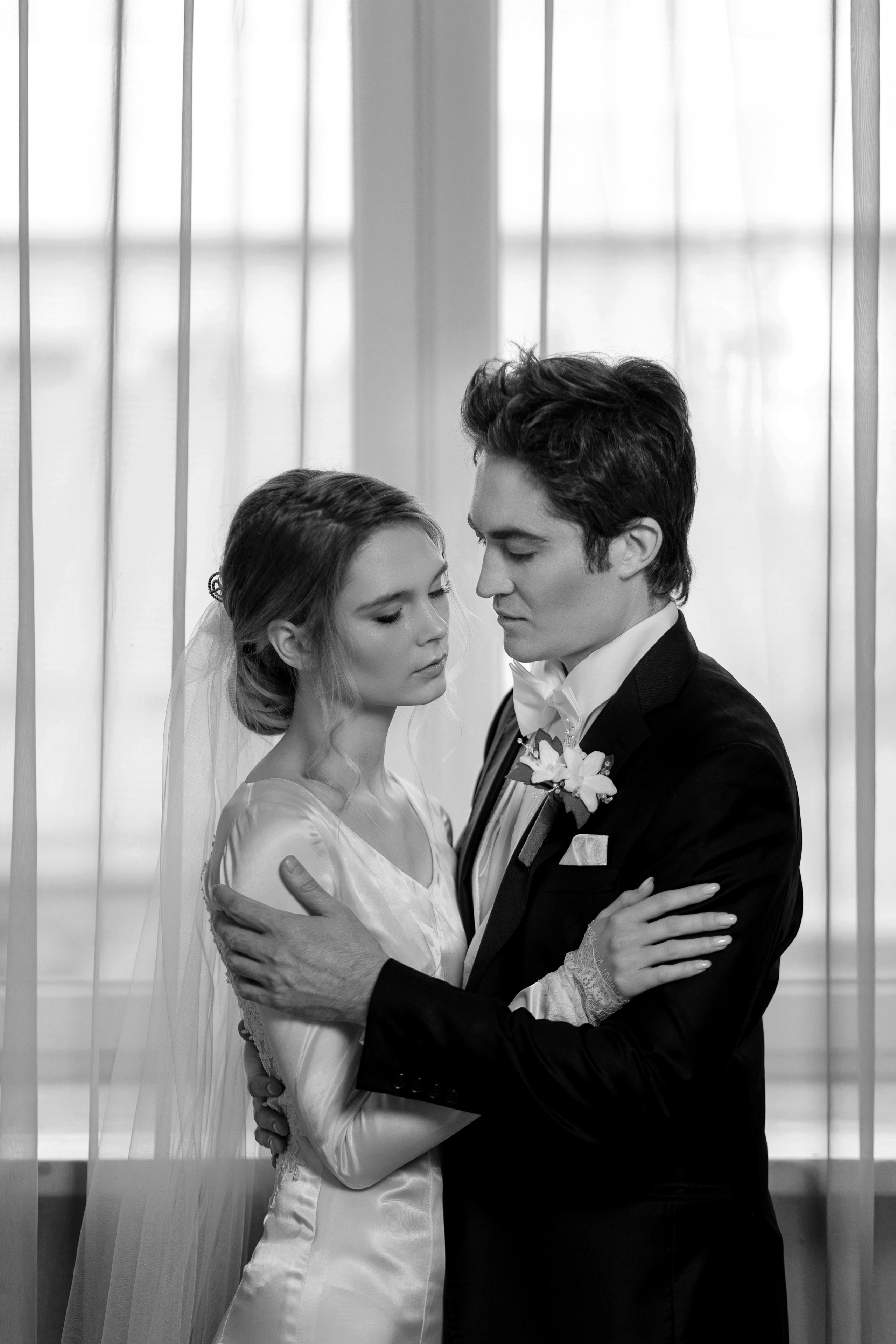 Жених и невеста на фоне окна в черно-белом цвете.