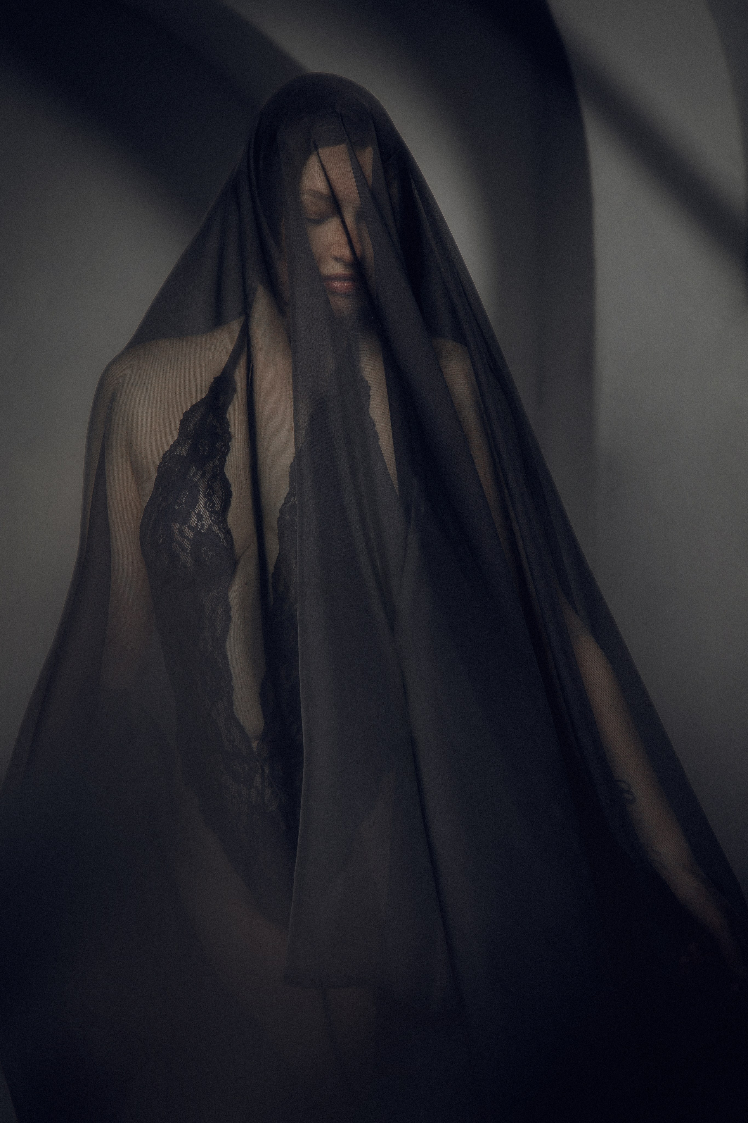 Загадочная портретная фотосессия с использованием длинных тканей создает эффект движения и динамики, подчеркивая красоту и грацию модели. Драматичный портрет с использованием темных тканей, подчеркивающих женственность и загадочность модели.