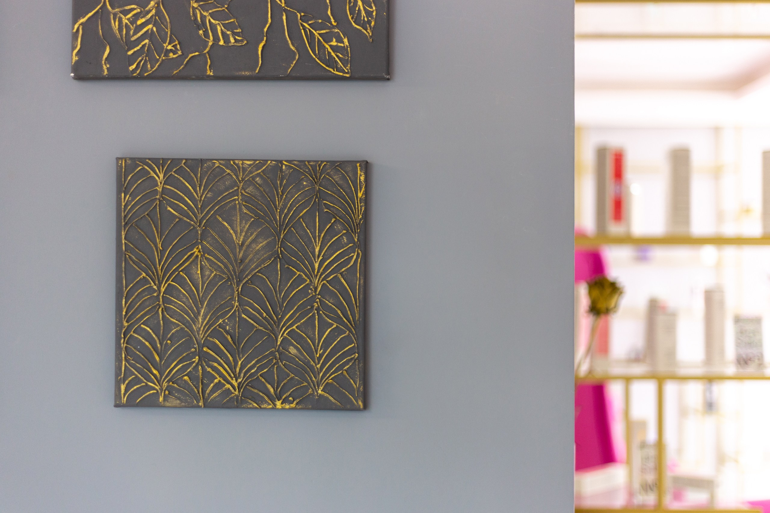 Современная картина с золотой патиной на серой стене.